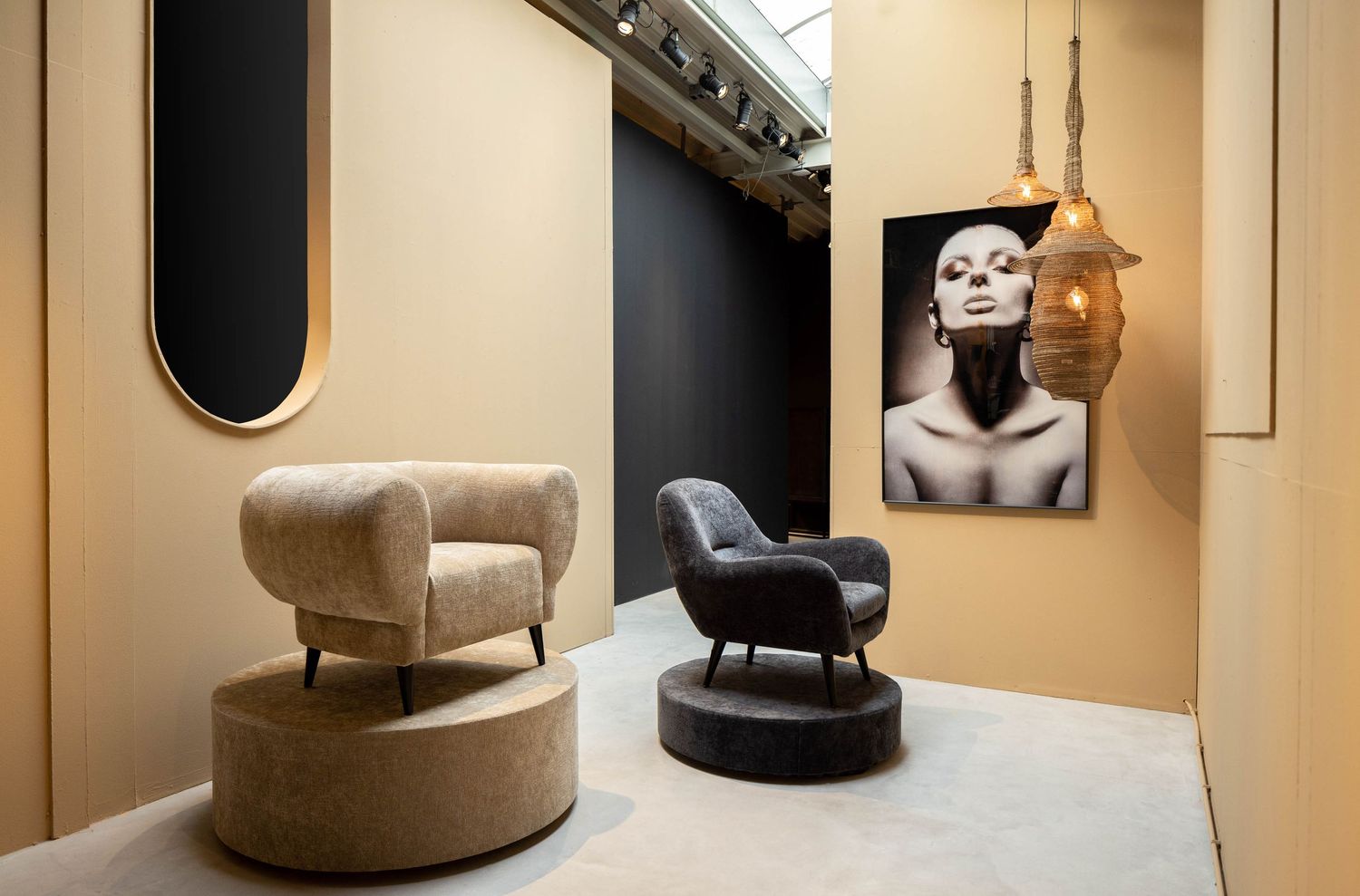 Modern interior design space with curved armchairs and black and white artwork on beige walls.