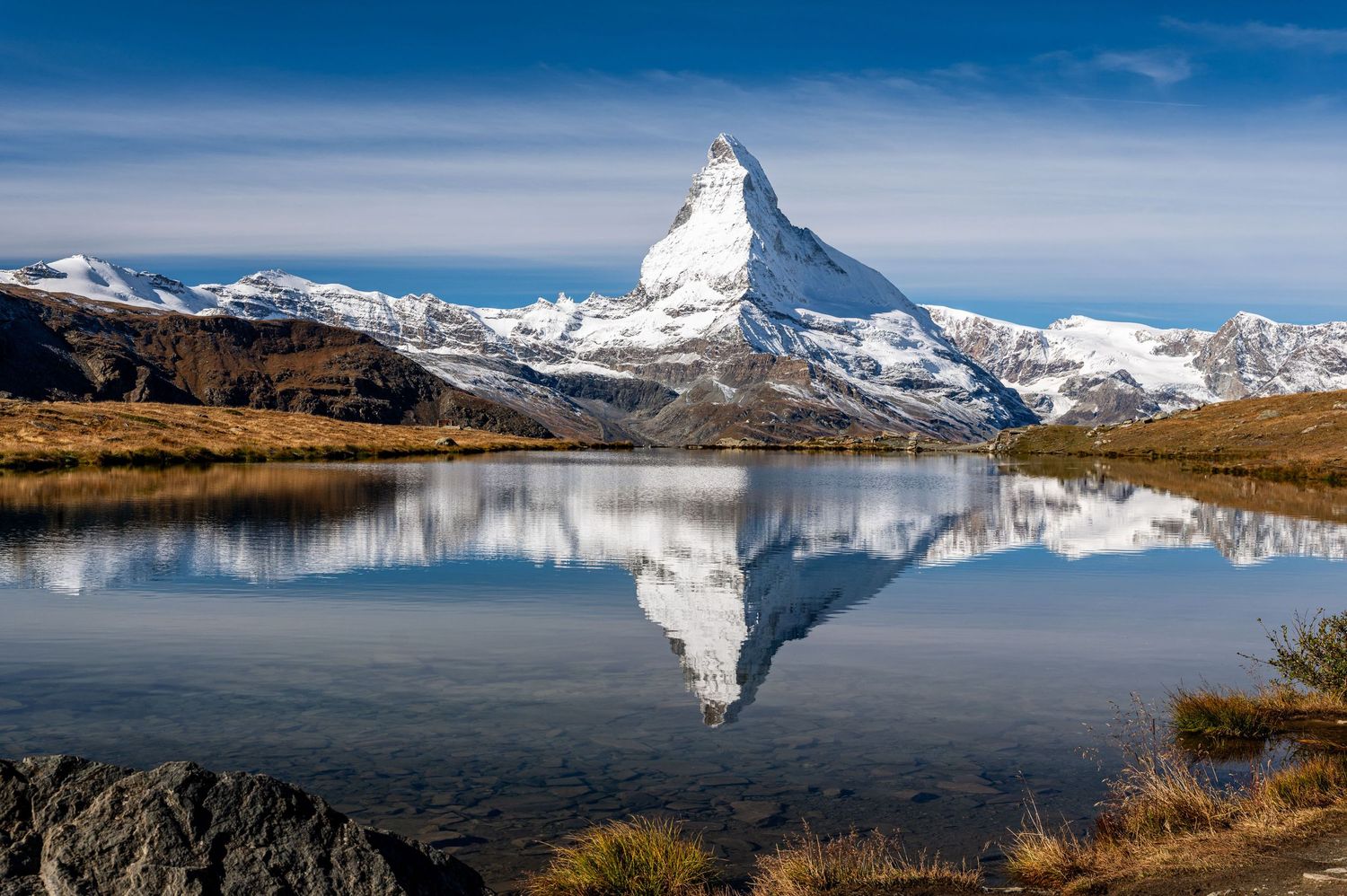 Stunning panorama of the Matterhorn mountain peak reflecting in crystal clear alpine lake waters.