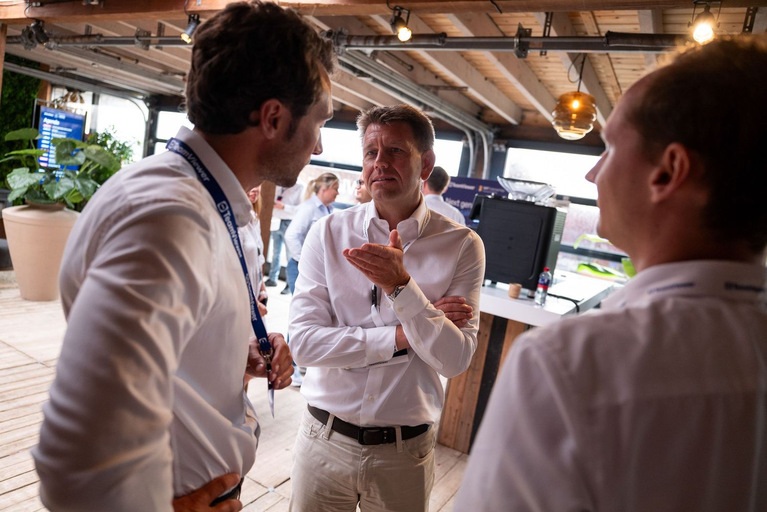 Business professionals networking during corporate event under wooden beams.