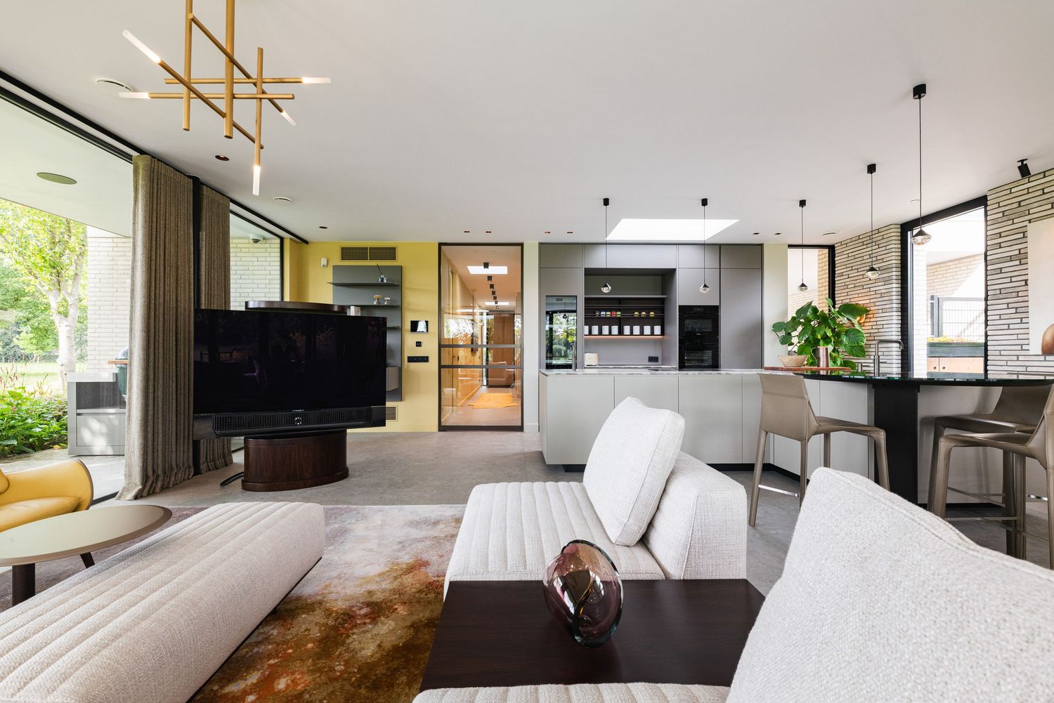 Modern living room interior with sleek furniture and natural light streaming through large windows.