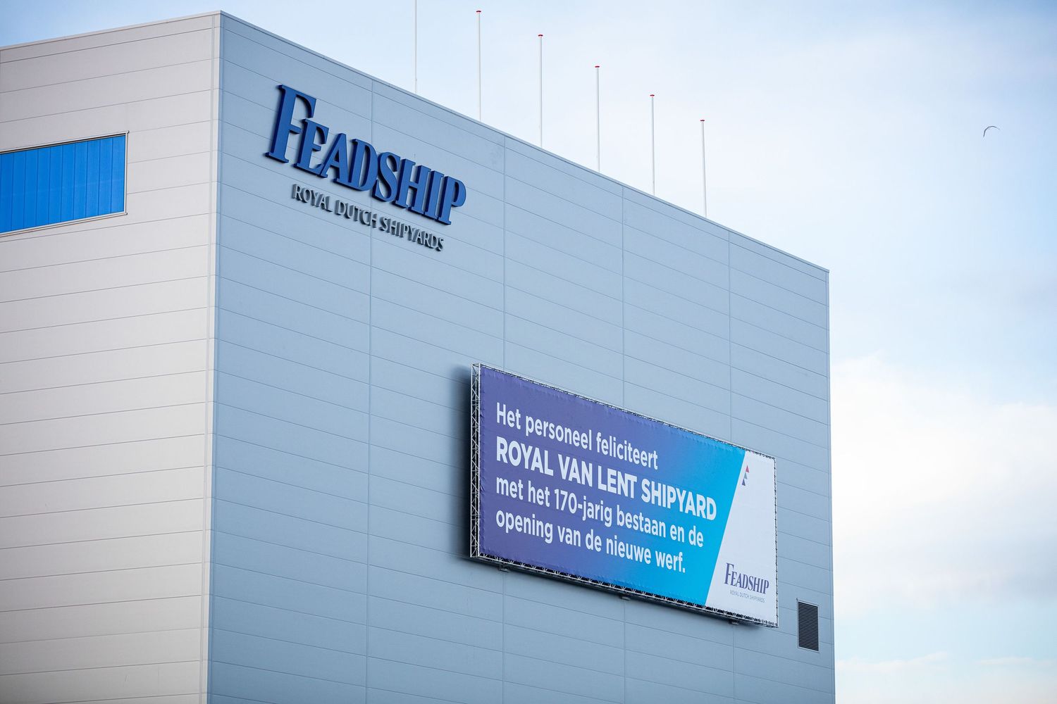 Large Pearson company sign mounted on white exterior building wall with blue sky in background.