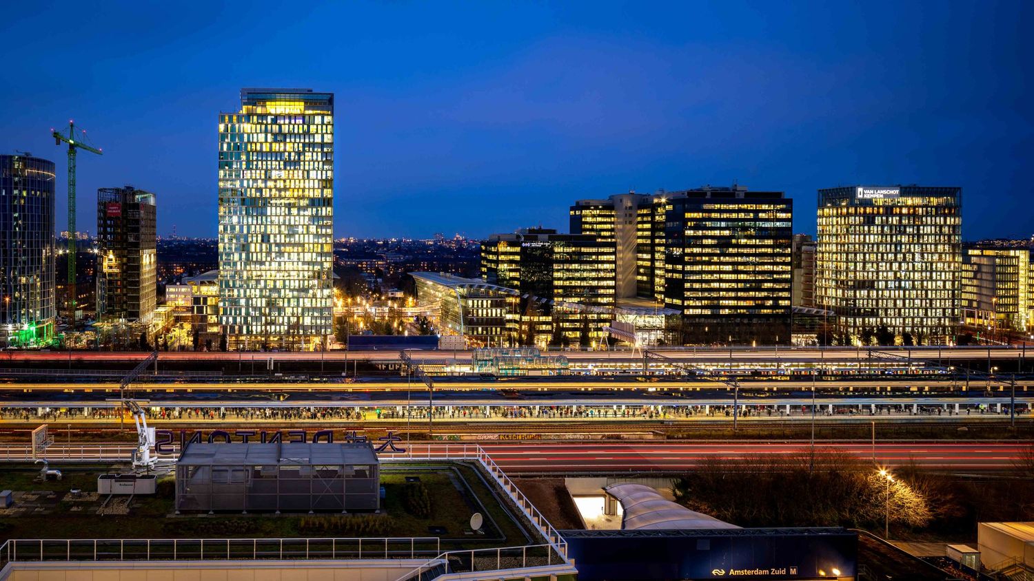 Illuminated Hamburg skyline at dusk reflects in the calm waters of the Elbe River with city lights glowing.