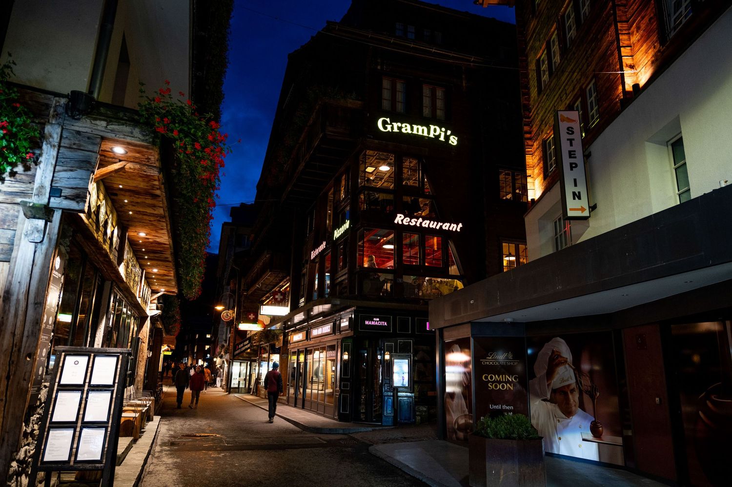 Illuminated cobblestone street at night with historic buildings and warm lighting.