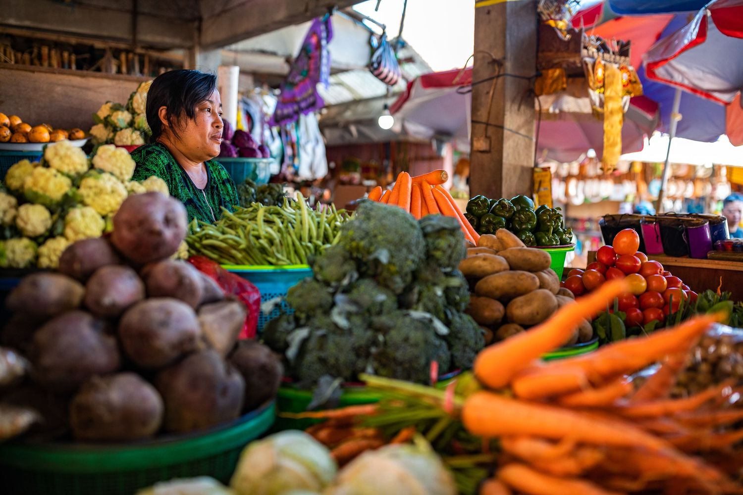 Colorful fresh produce display at local market with carrots, grapes and vegetables.