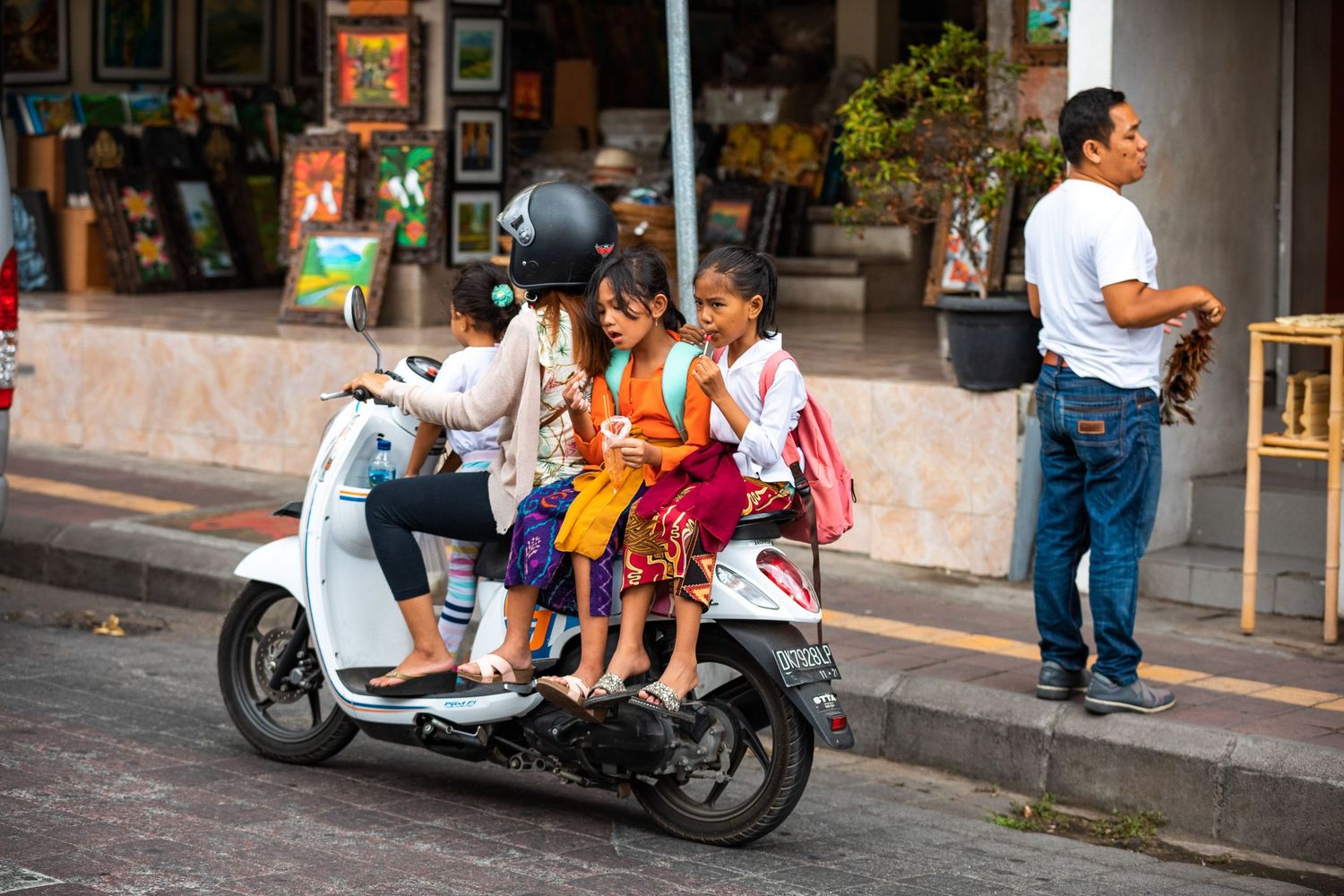 Street scene with motorcycles and pedestrians walking past local shops.