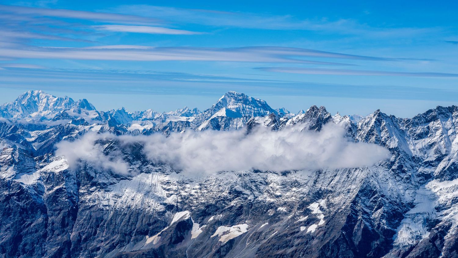Panoramic vista of jagged snow-capped mountain peaks stretching across the horizon.