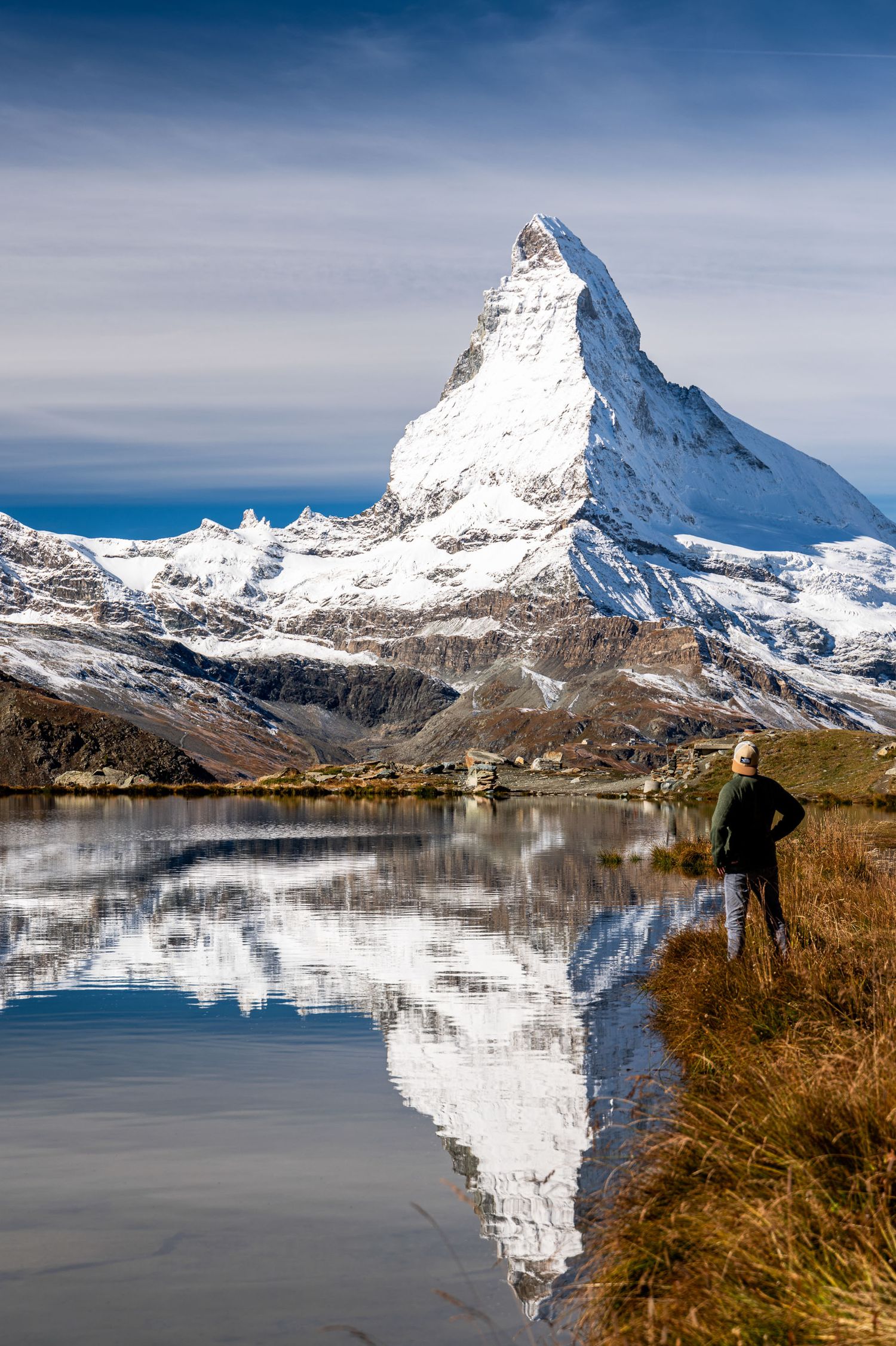 Snow-covered Matterhorn peak reflecting in the calm waters of Stellisee lake during winter.