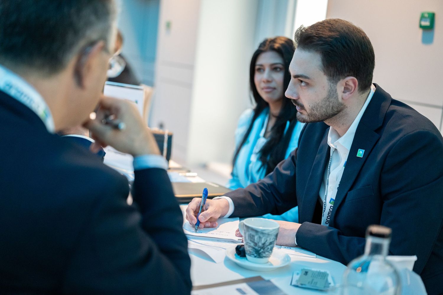 Business professionals engaged in discussion at a meeting table with laptops.