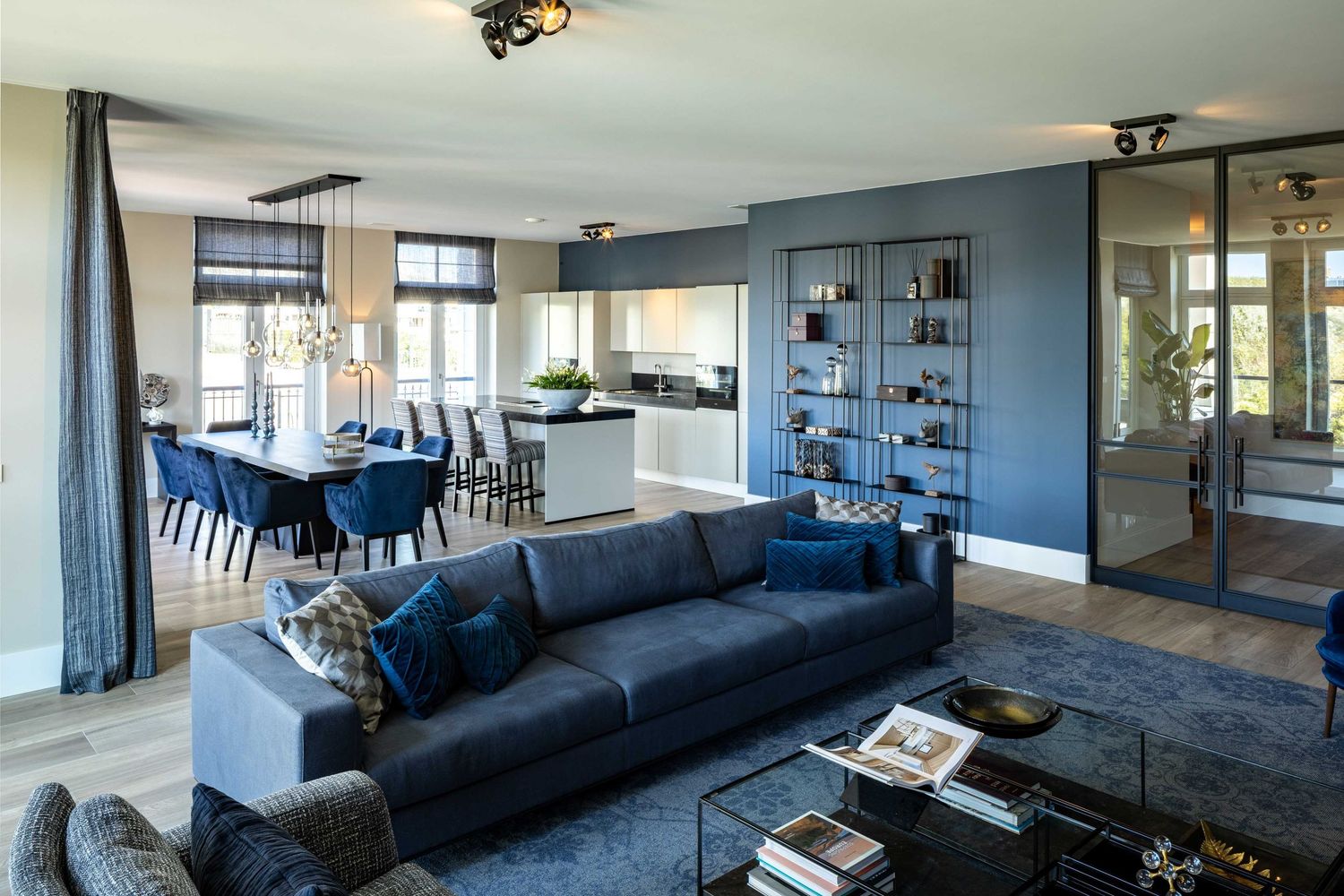 Modern living room interior with navy blue sectional sofa, glass walls, and sleek contemporary furnishings.