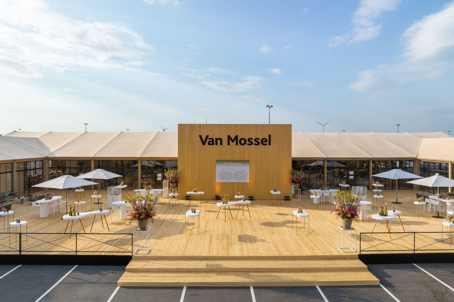 A modern car dealership exterior with yellow signage and outdoor parking area under blue skies.