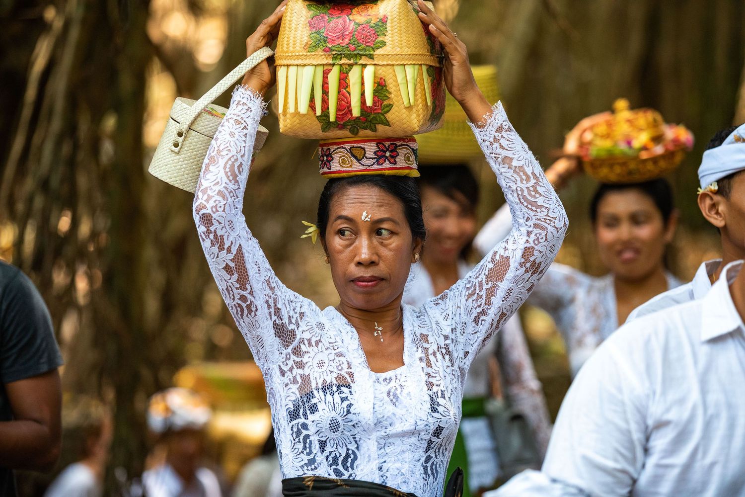 Traditional Balinese ceremony participants in white and gold attire.
