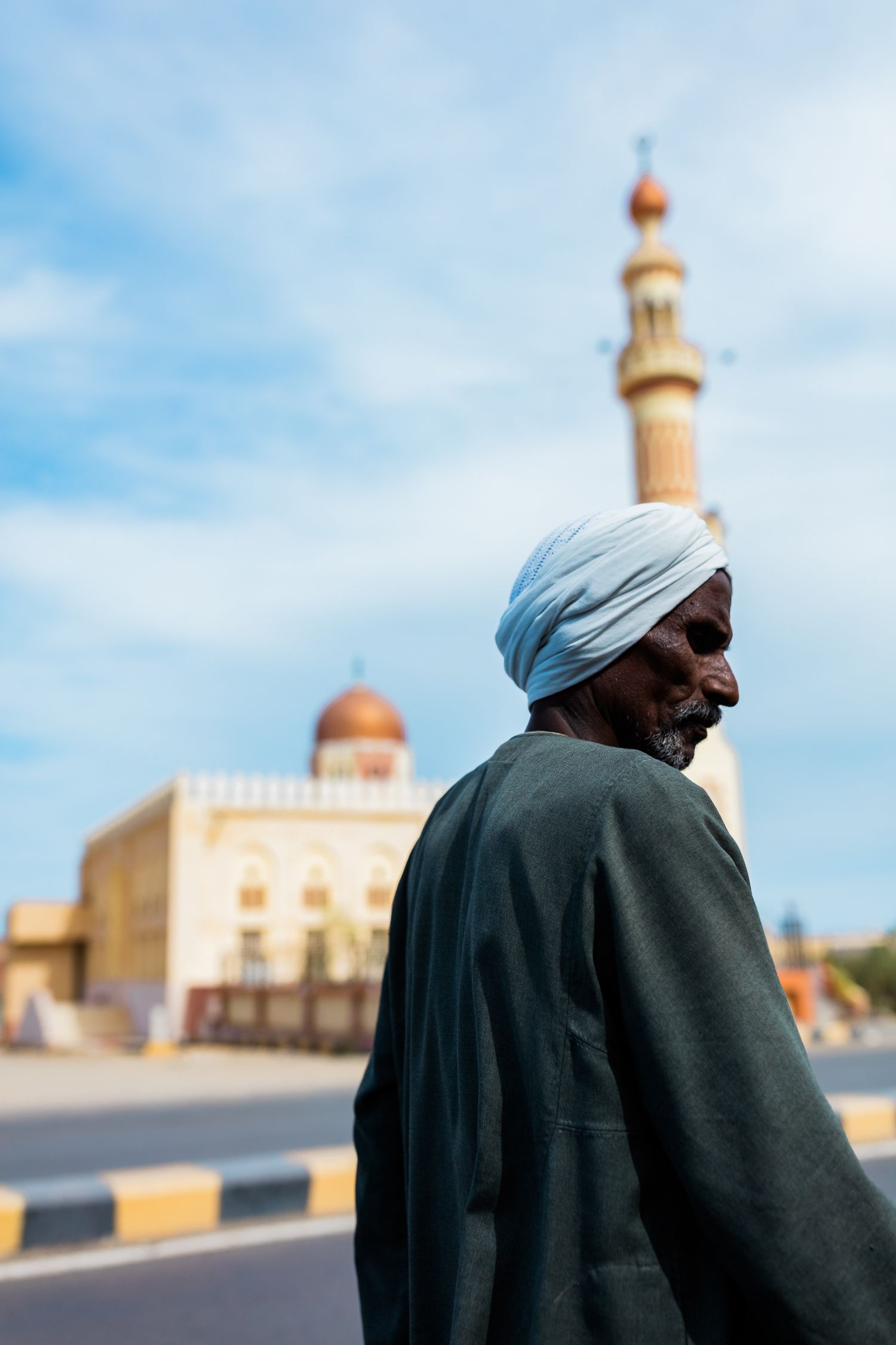 Traditional Middle Eastern architecture with domed mosque and minarets against blue sky.