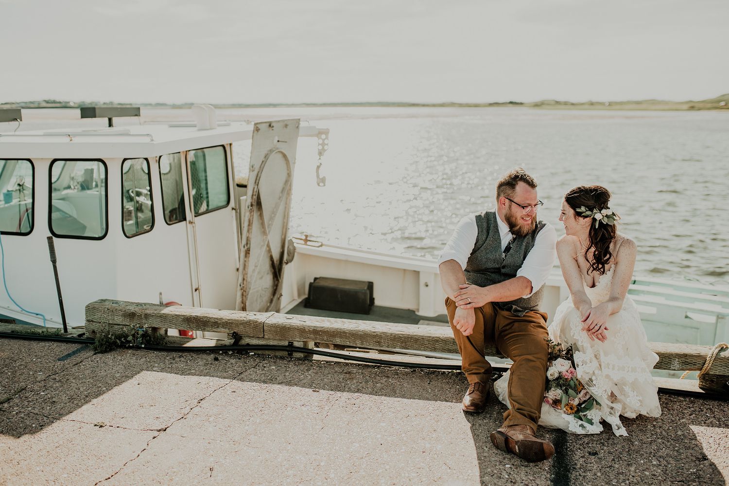 Bride & Groom laugh together by the ocean at the Brackley Beach, PEI wedding.