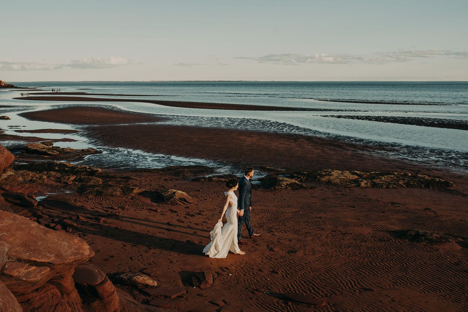 Bride & Groom walk on the red sand beach on their wedding day near Charlottetown, PEI