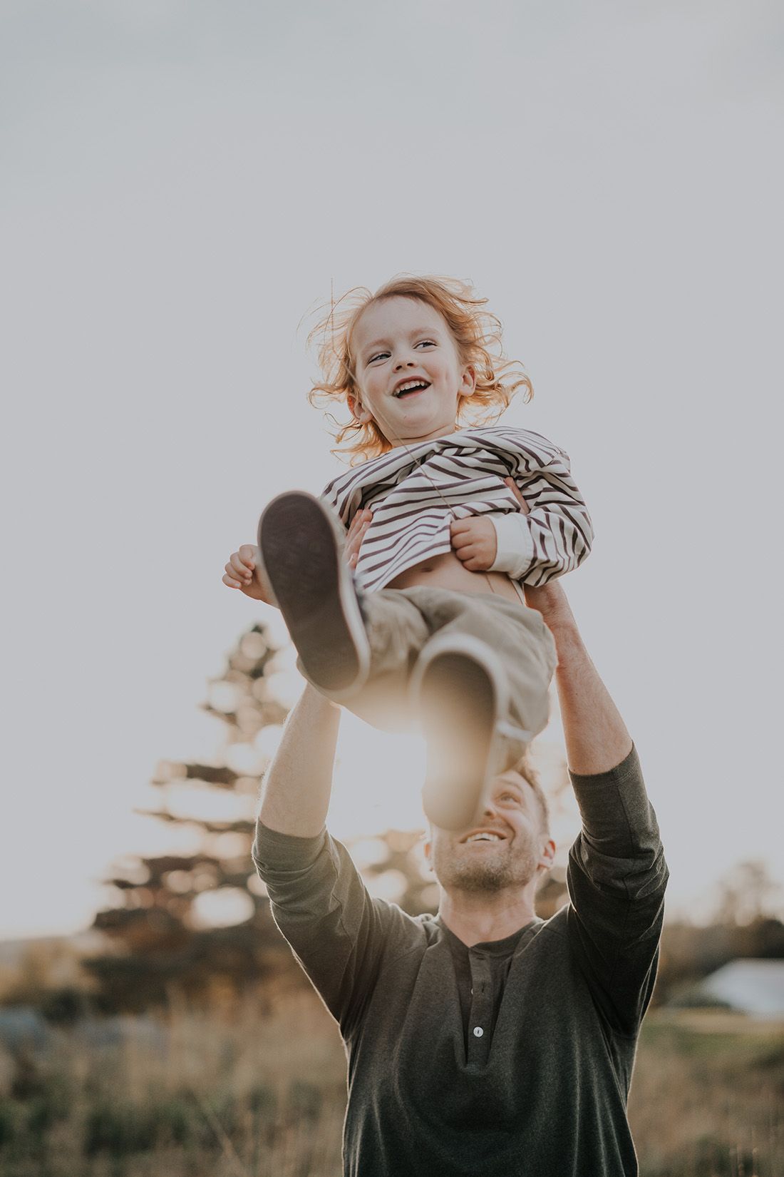 A little boy being tossed in the air by his dad during family photos with Heather Wilkinson in Bristol, New Brunswick.