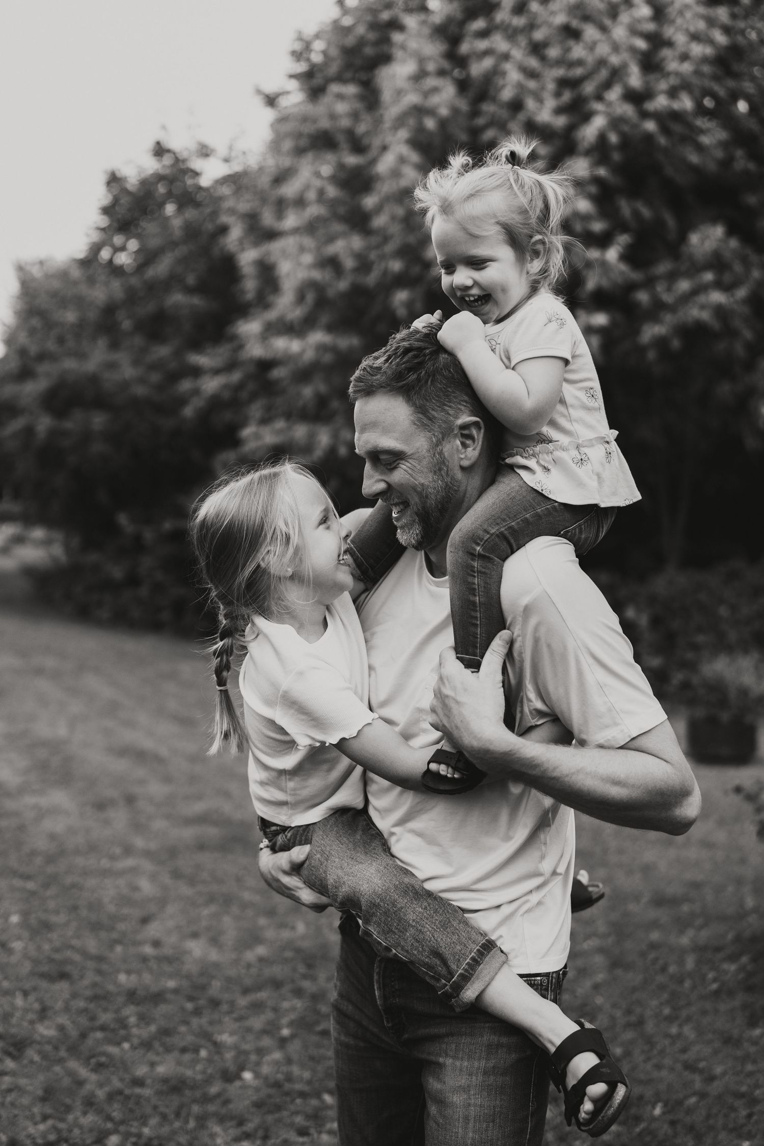 A dad carries his daughters during family photos in Woodstock, New Brunswick