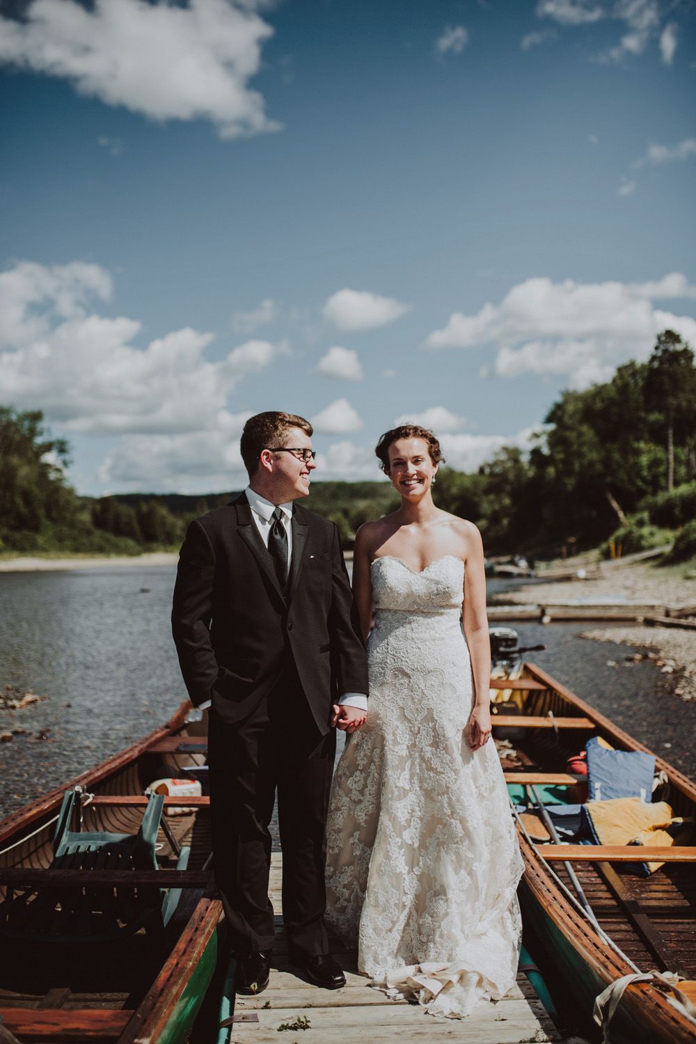 A couple stand on a dock with boats at their Campbellton, New Brunswick wedding.