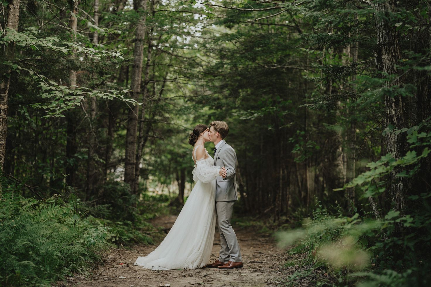 A bride and groom kiss in the woods on their wedding day in New Brunswick.