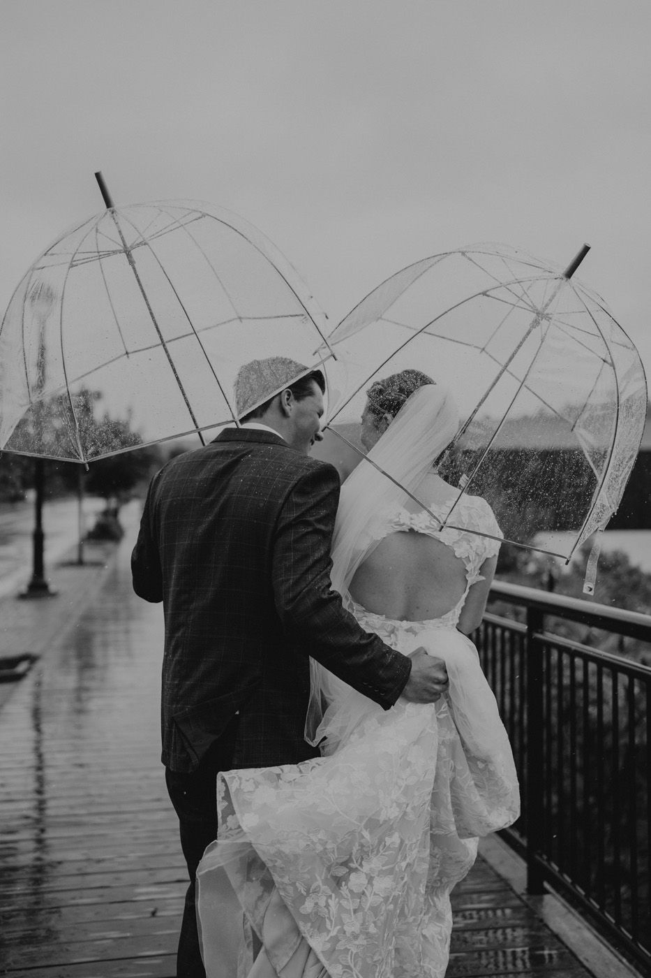 A couple walk in the rain with umbrellas on their wedding day in Florenceville-Bristol, New Brunswick