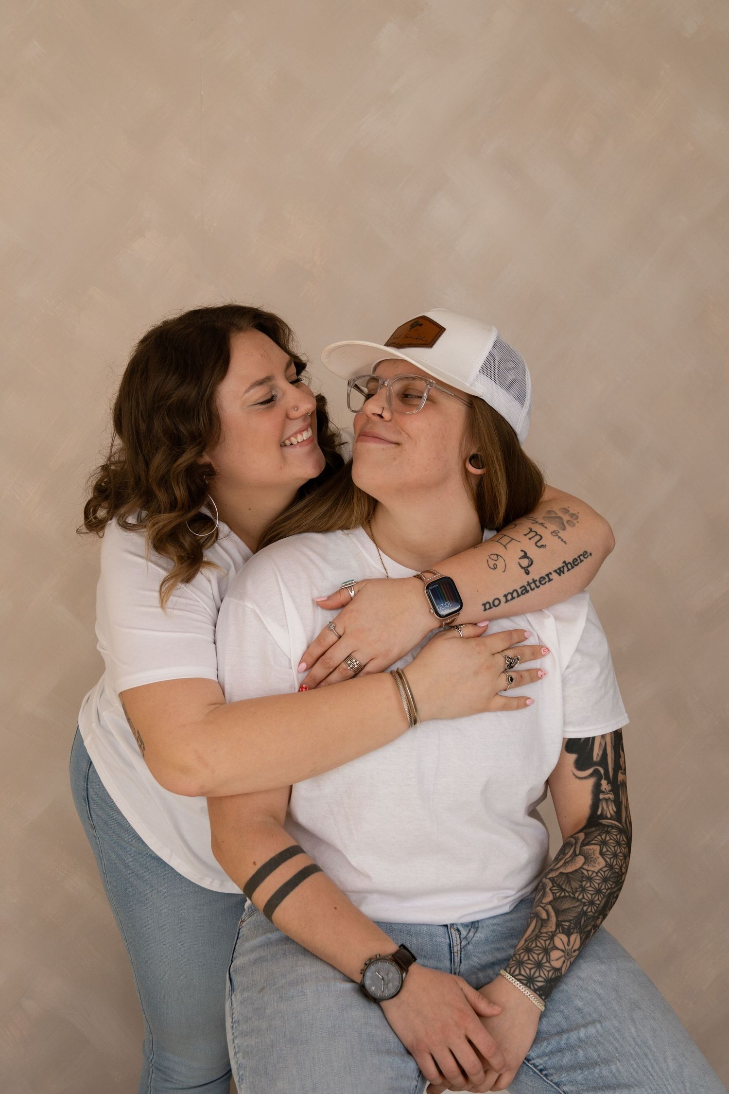 Intimate couple in white shirts and jeans share tender moments in a studio photoshoot.