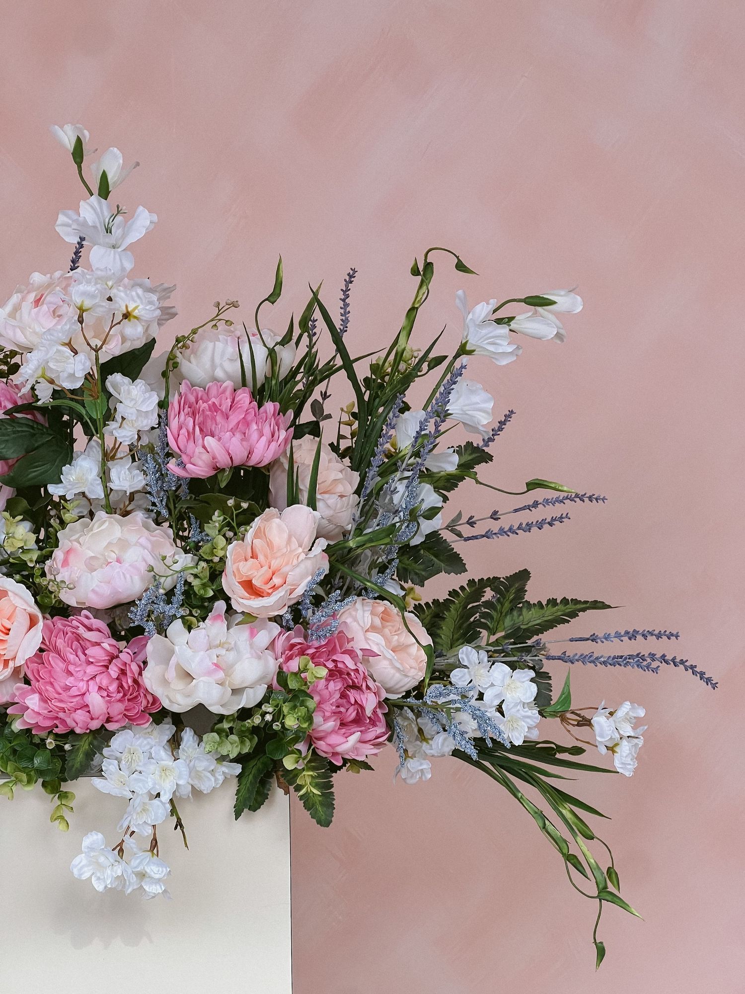 Elegant floral arrangement with pink and white flowers against blush background.