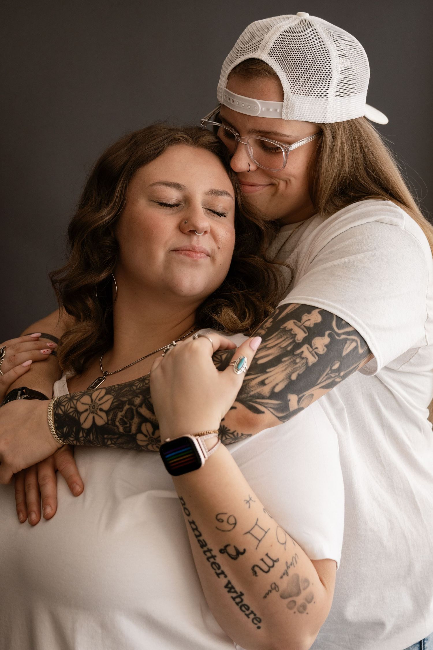 An intimate couple's portrait showing tattoos and embraces in moody lighting.