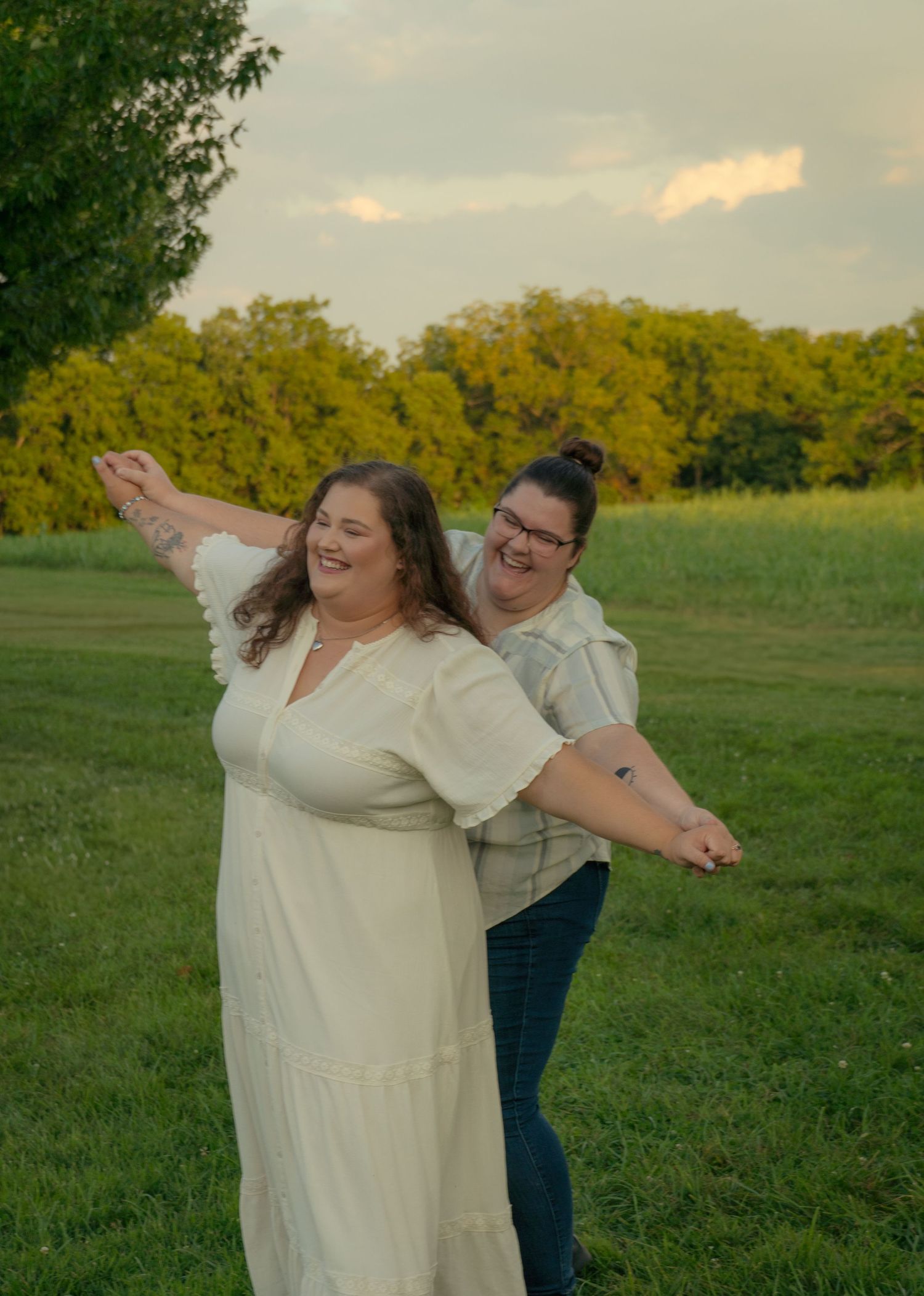 Joyful couple playing and dancing together in a green field at sunset.