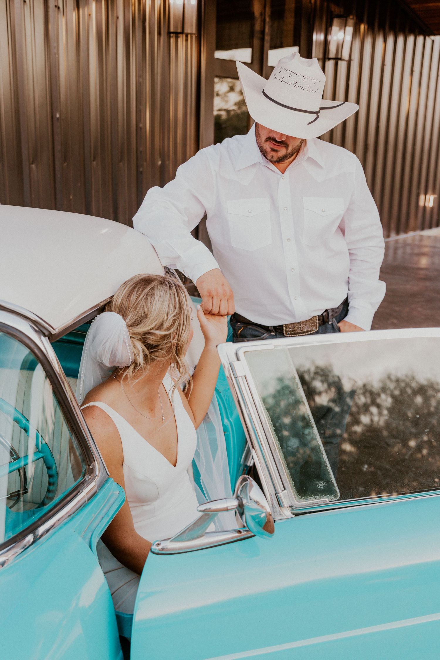 Bride sits in a turquoise vintage car and looks over her shoulder at her new husband.