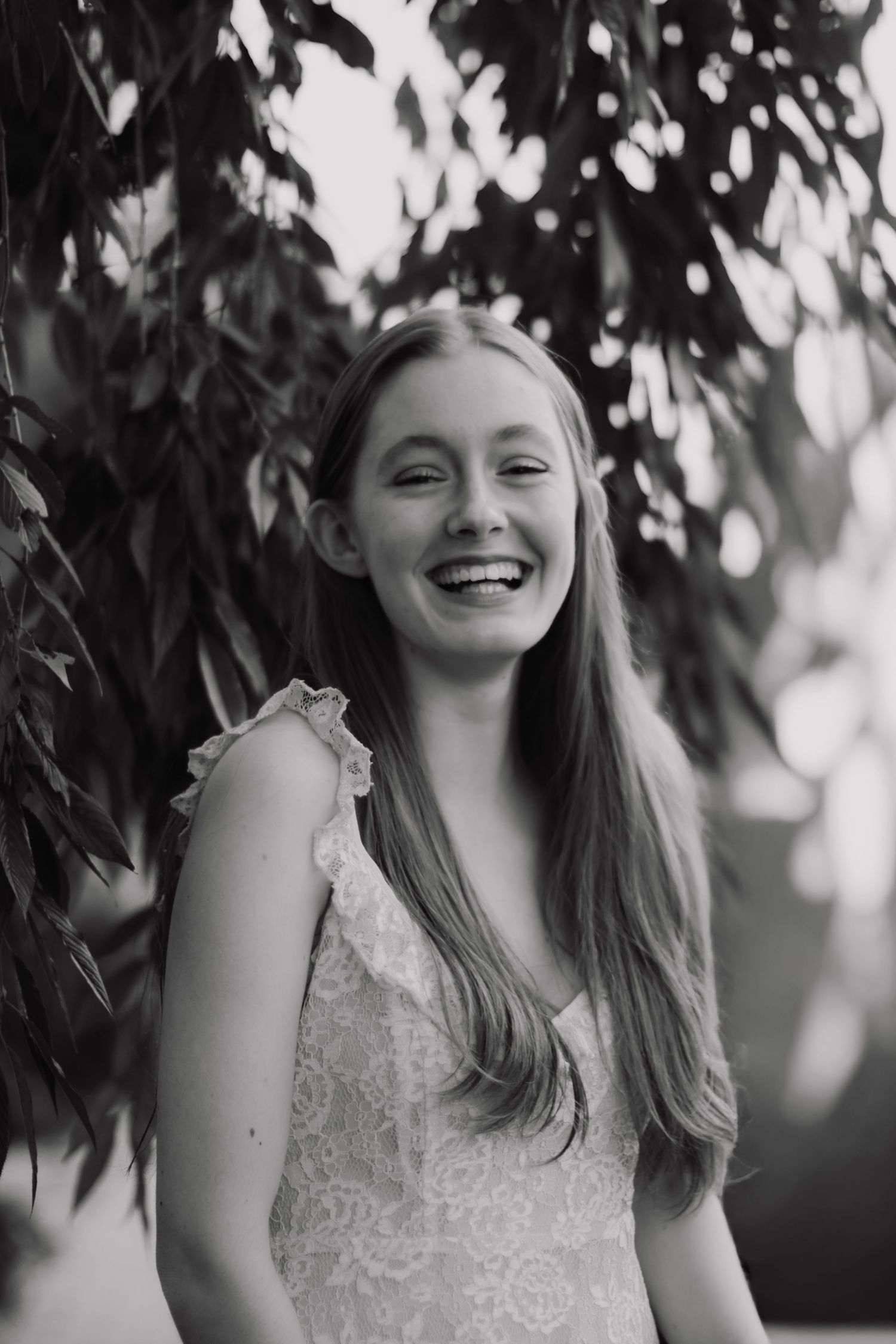 Black and white portrait with natural lighting and foliage backdrop.