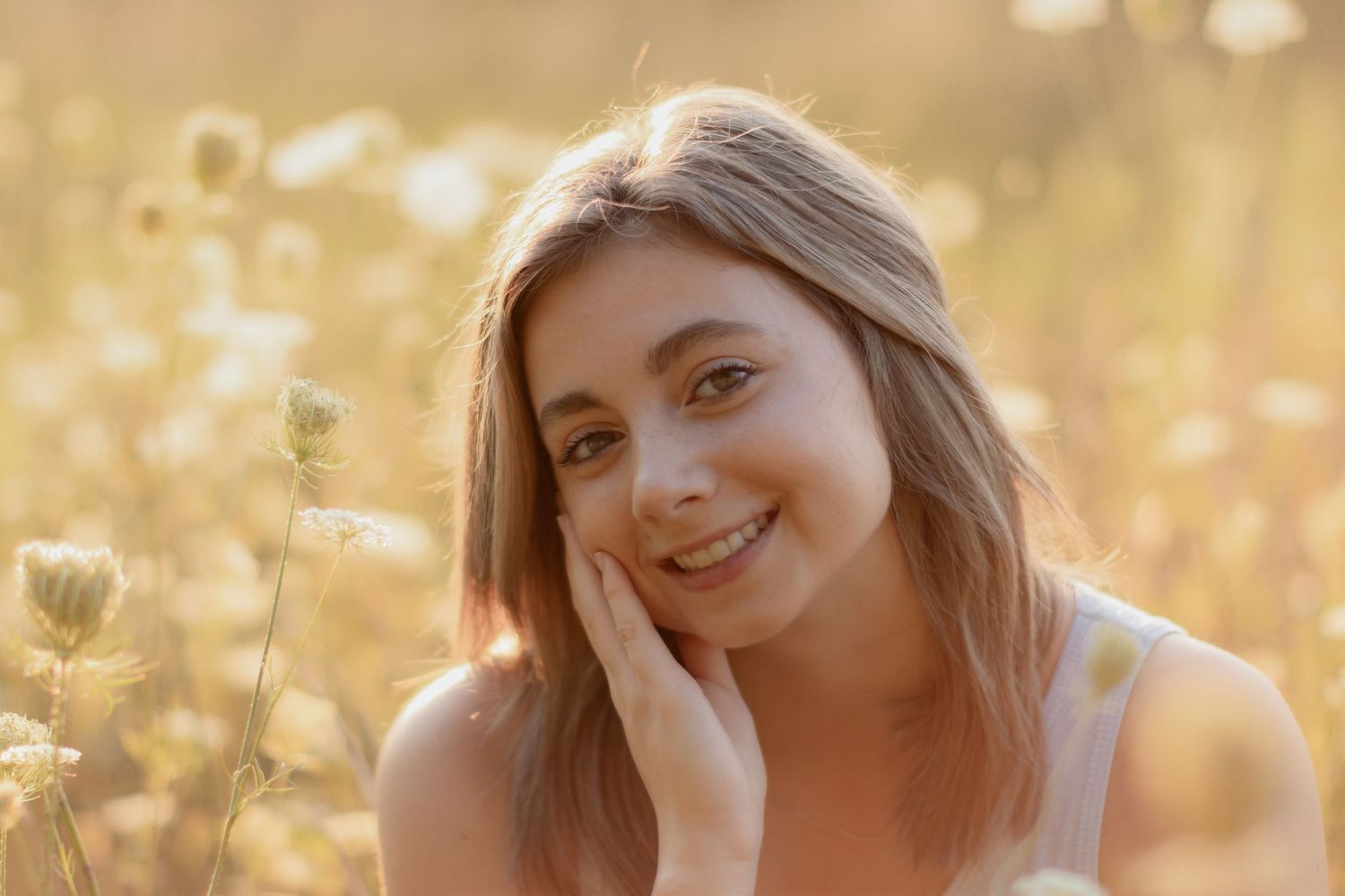 A person posing in a field during golden hour with soft natural lighting.