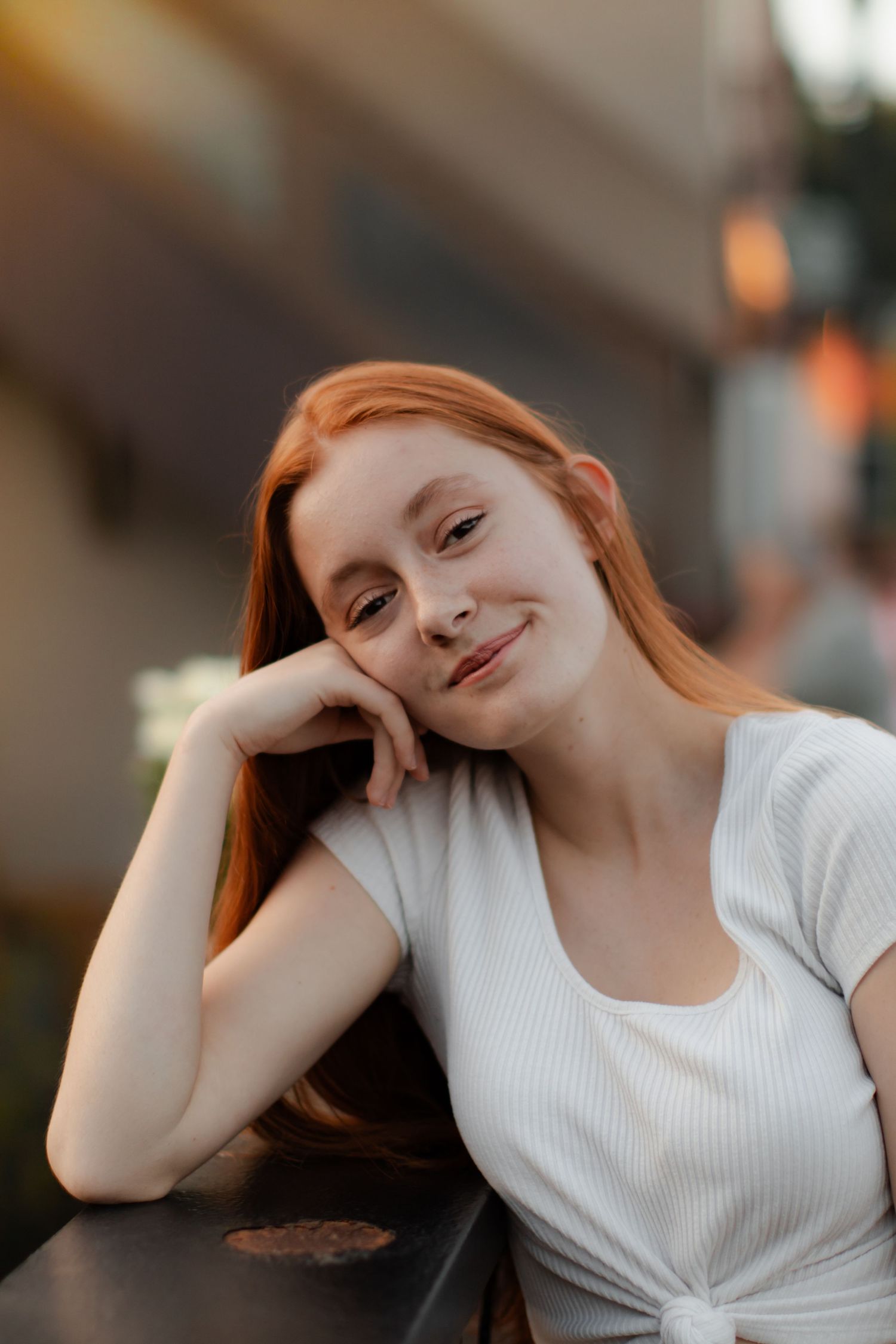 A person in a white top posing with casual, relaxed expressions against a blurred background.