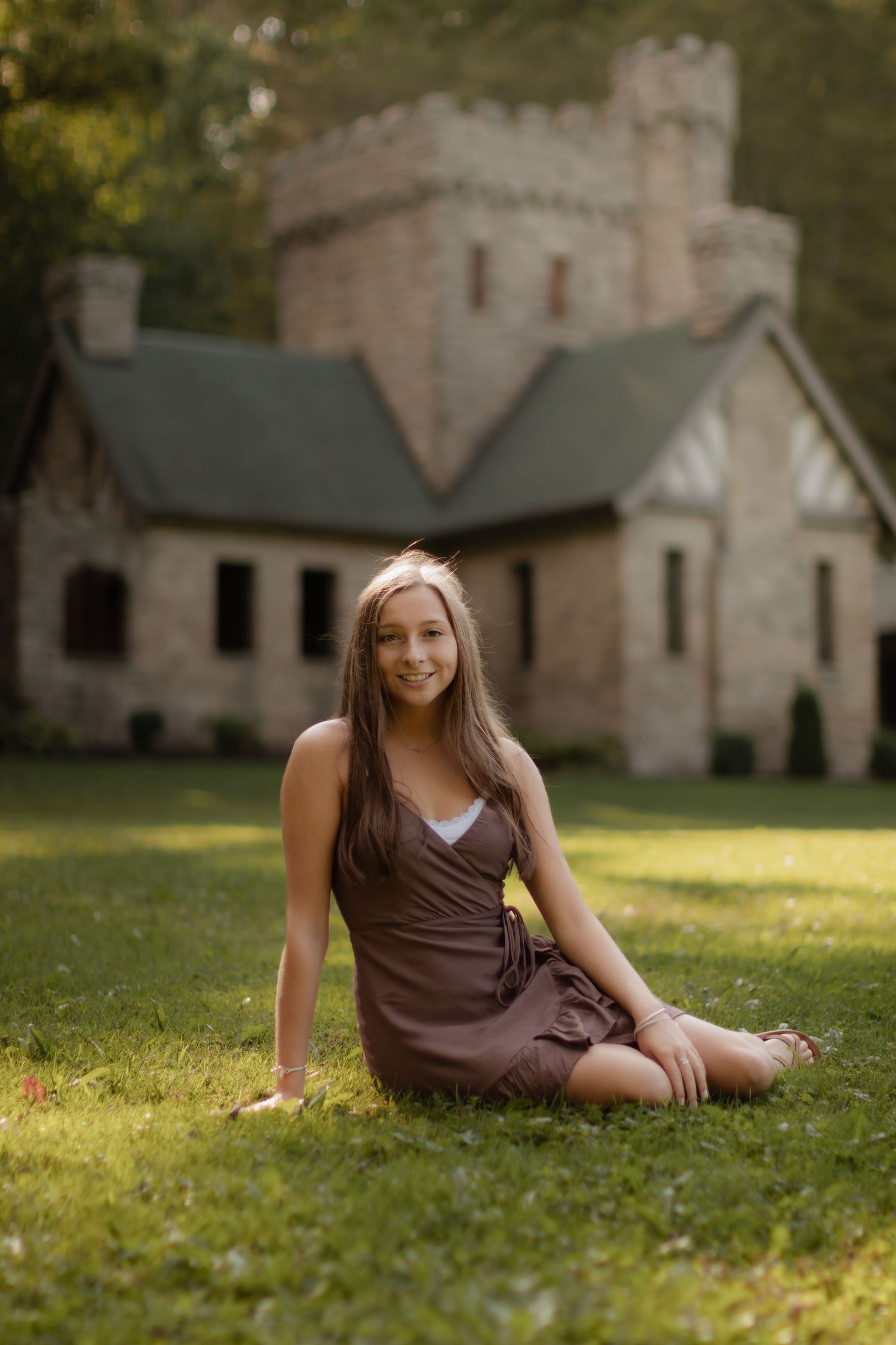 A person lying on grass with a historic stone building visible in the background.