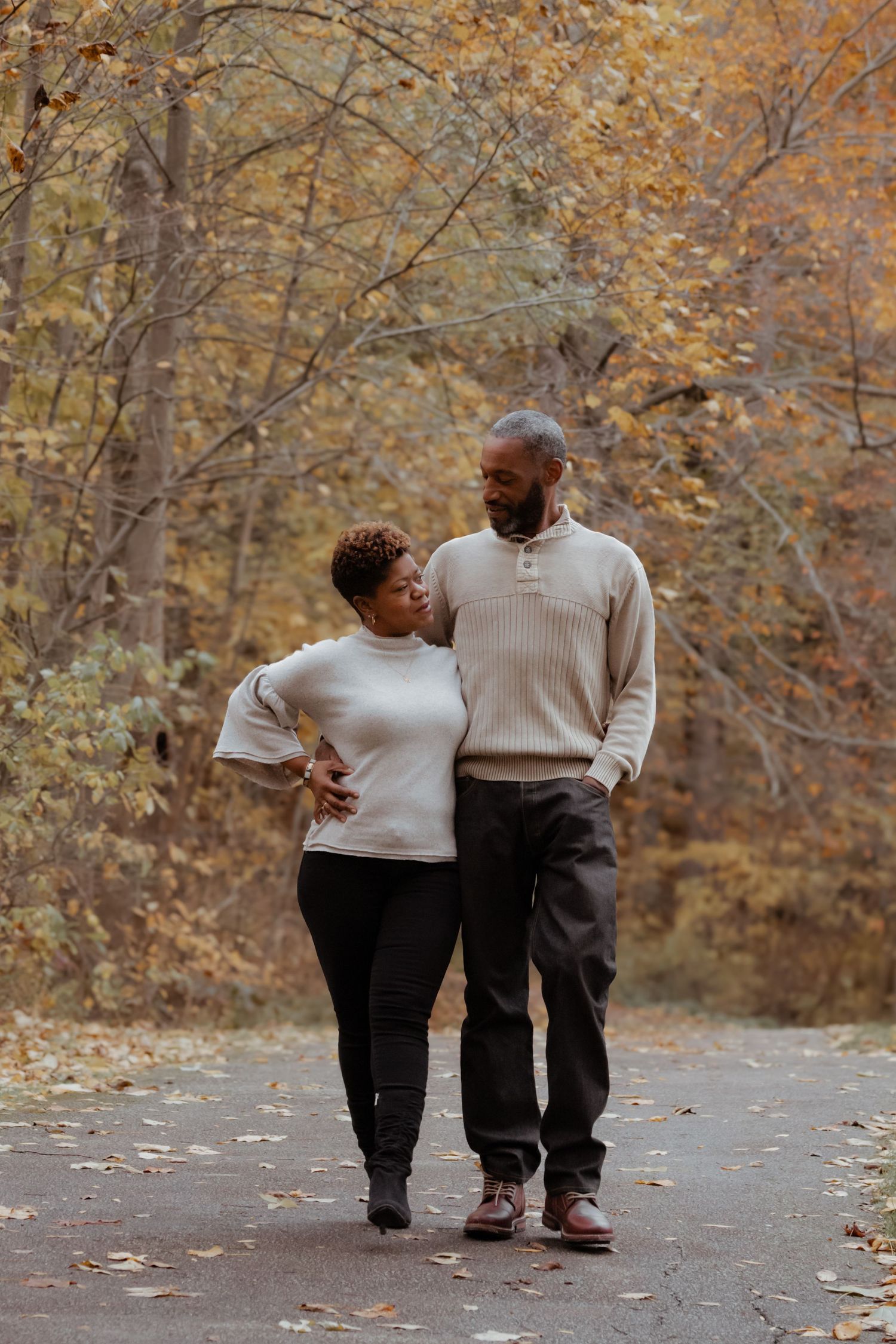 Couple takes romantic autumn walk together on leaf-covered path.