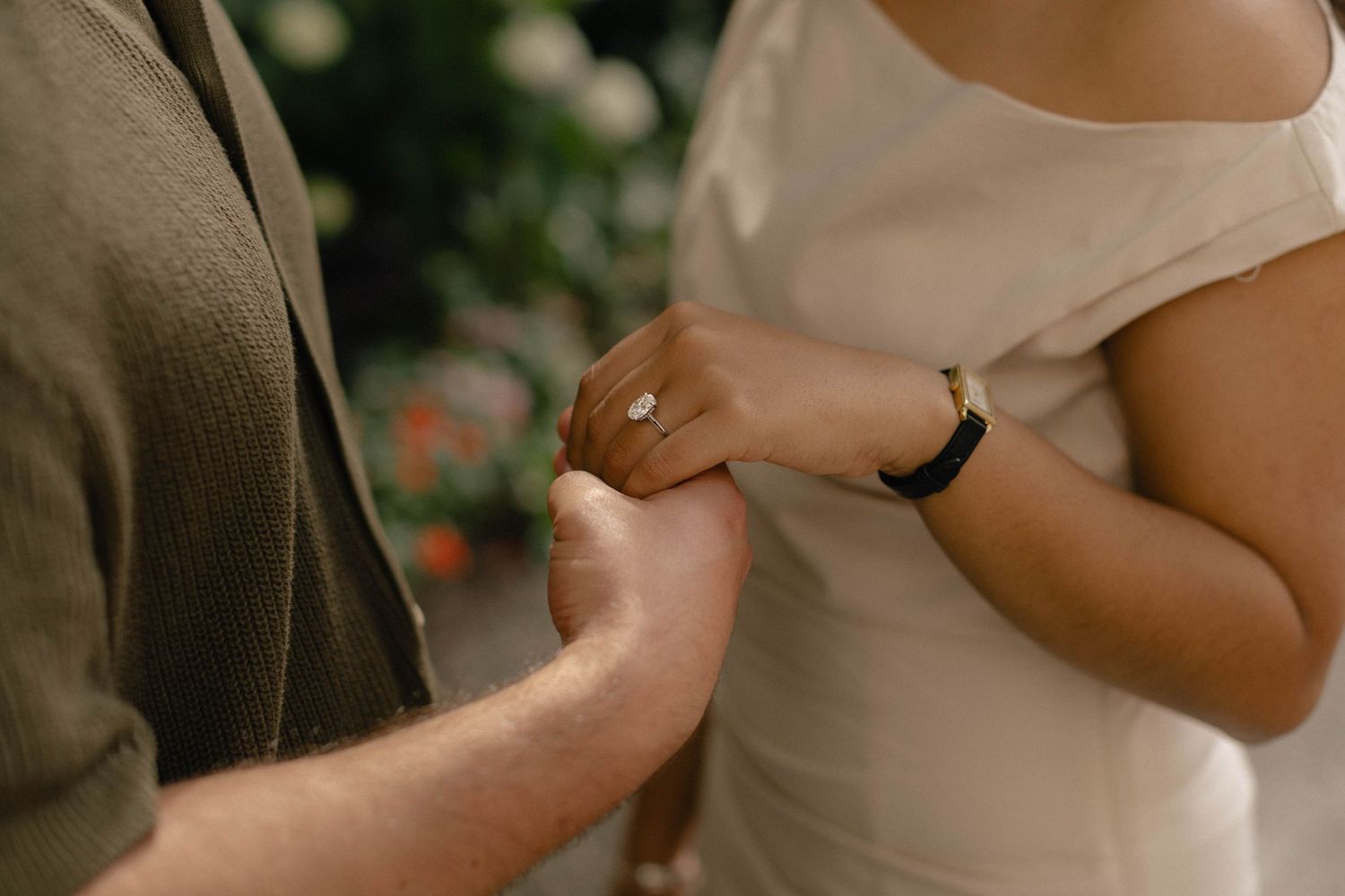 Close-up of a couple sharing a tender moment as a man places a ring on a woman's finger during a proposal.