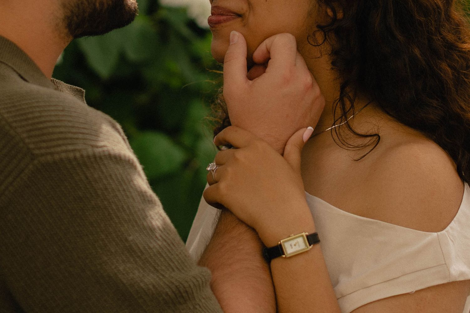 Close-up of a couple sharing an intimate moment, woman wearing a gold watch touching mans face.