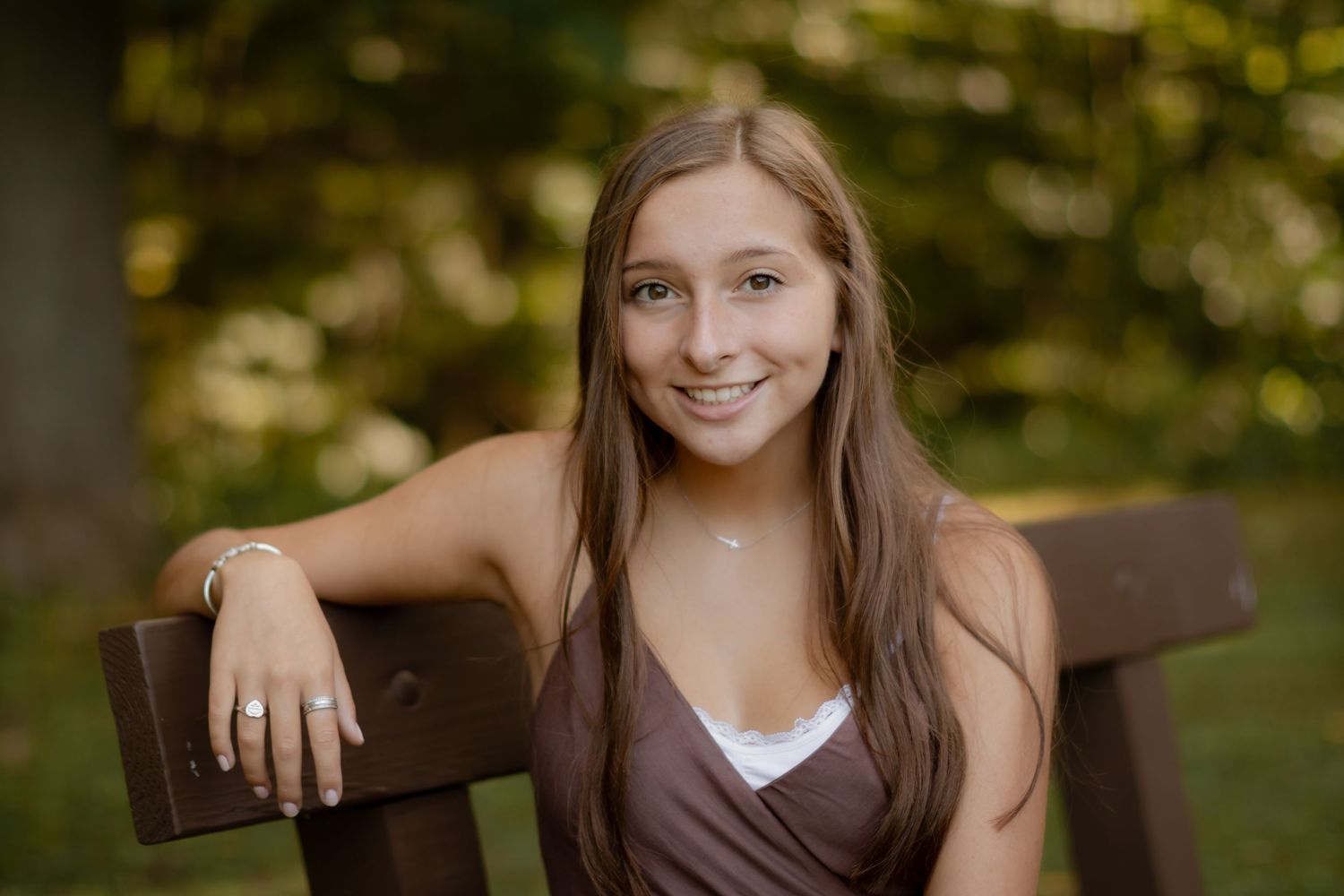 A person sitting outdoors with a warm smile against a bokeh background.