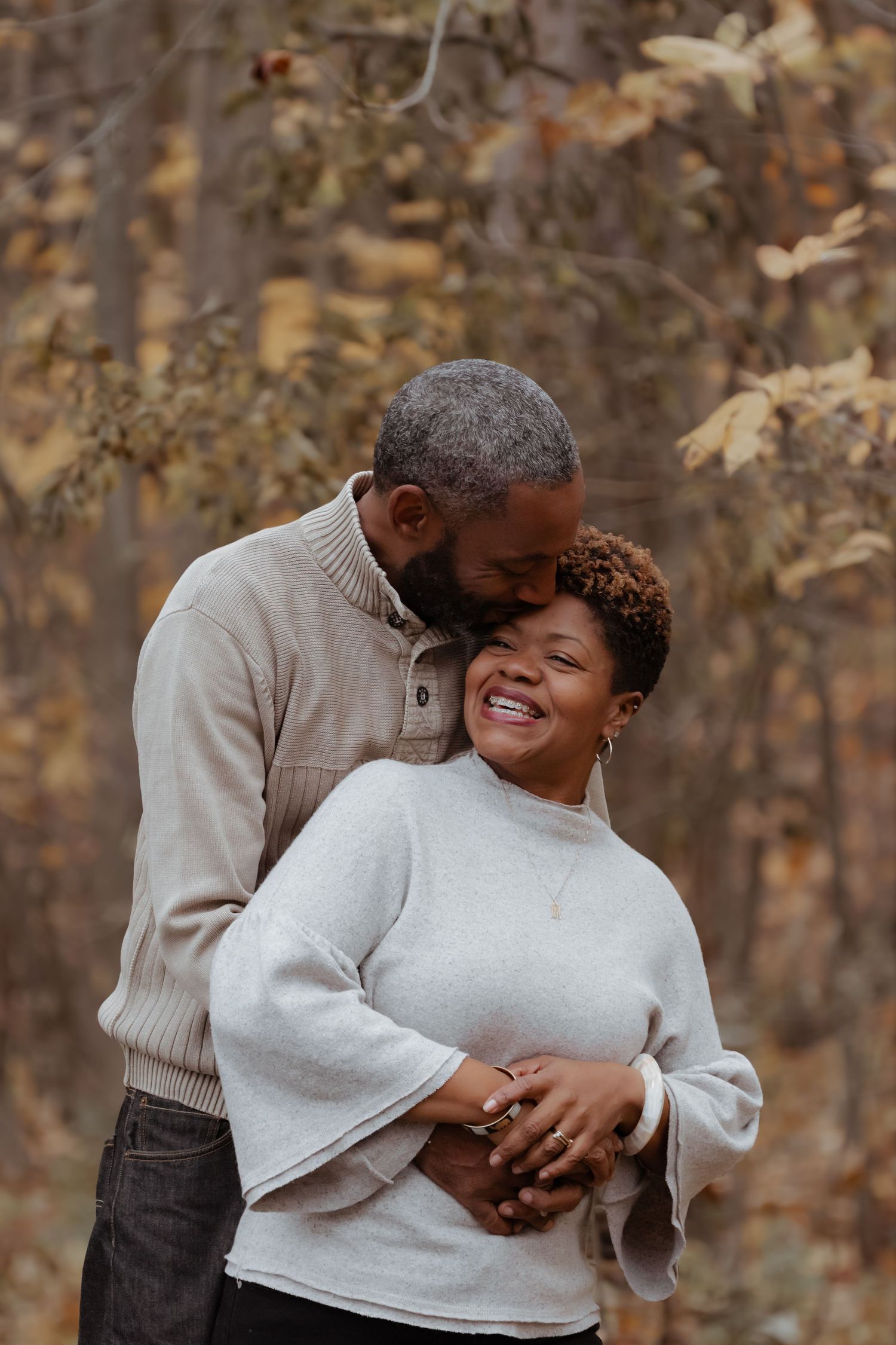 Couple shares loving embrace during autumn photoshoot in cozy sweaters.