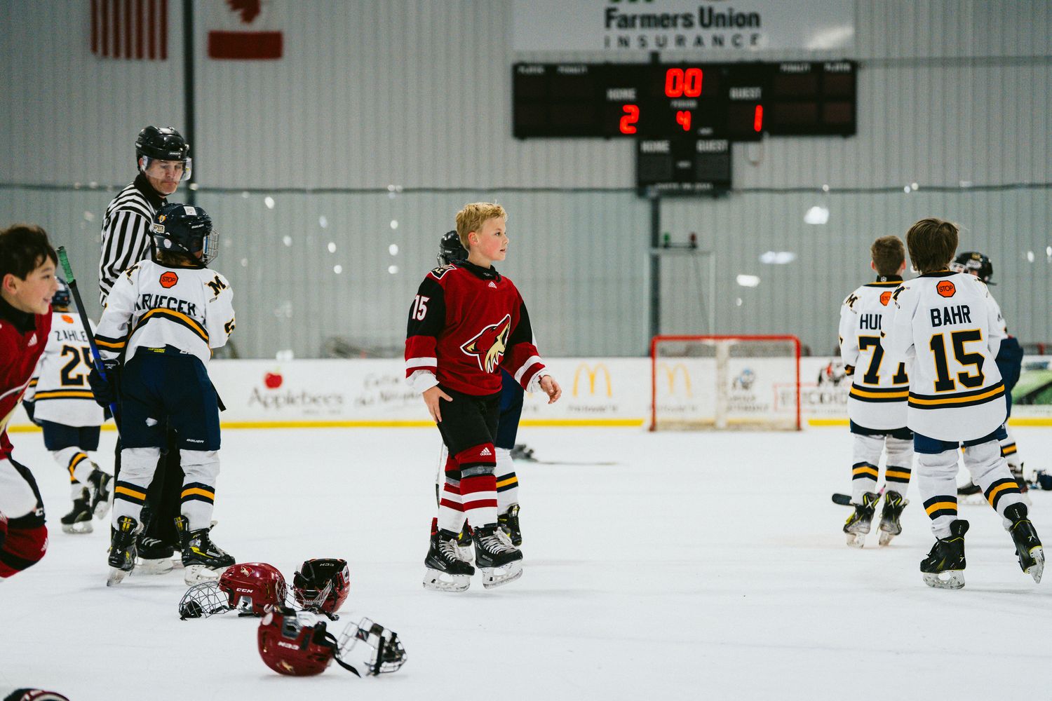 Youth hockey practice session on indoor rink with players spread across the ice.