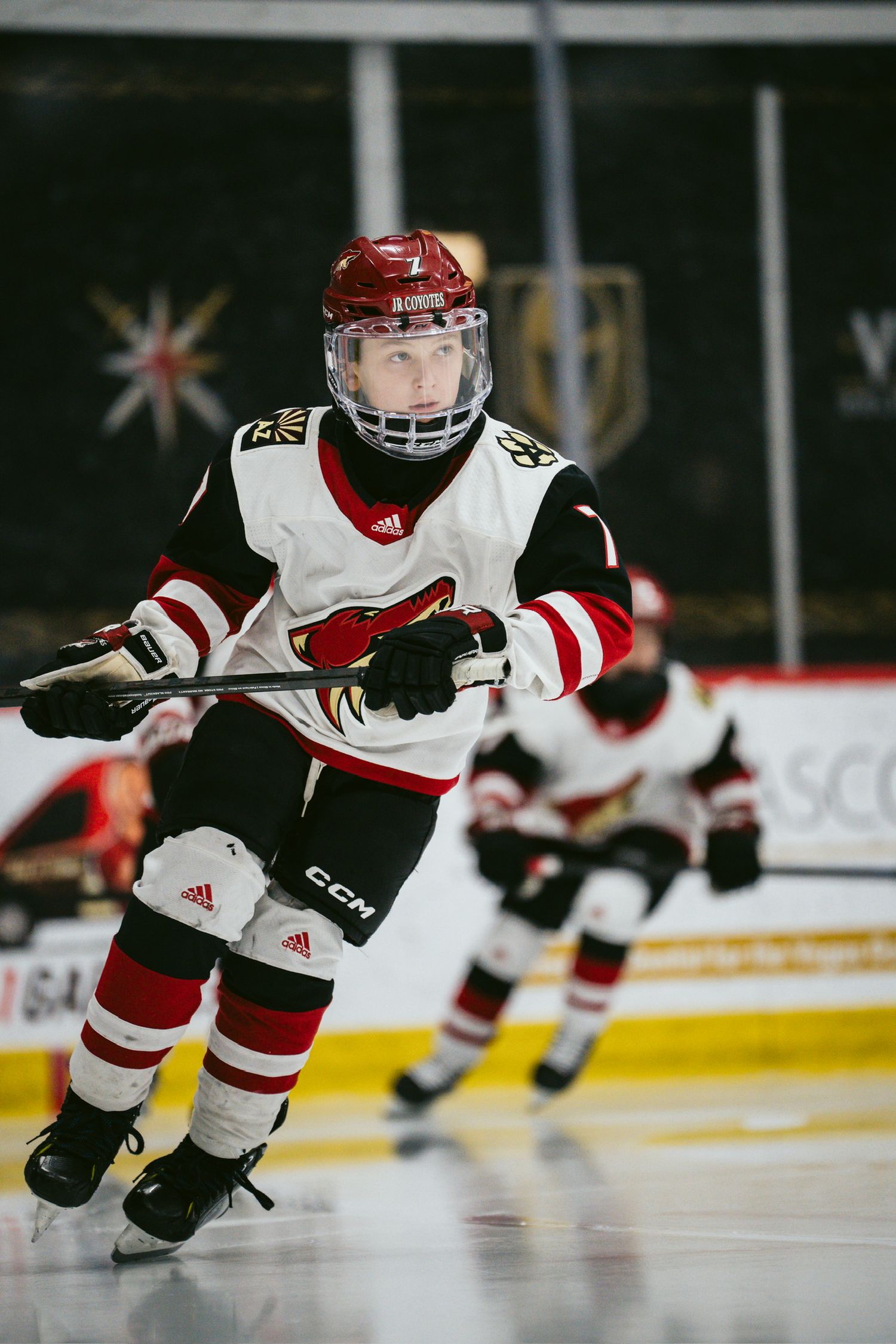 Youth hockey players in red and white uniforms glide across the ice during a game.
