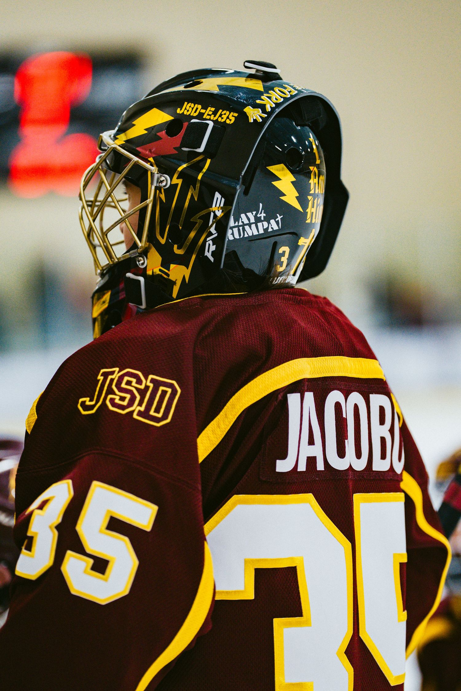 Close-up of hockey players' jerseys showing team numbers and nameplates in brown and gold colors.