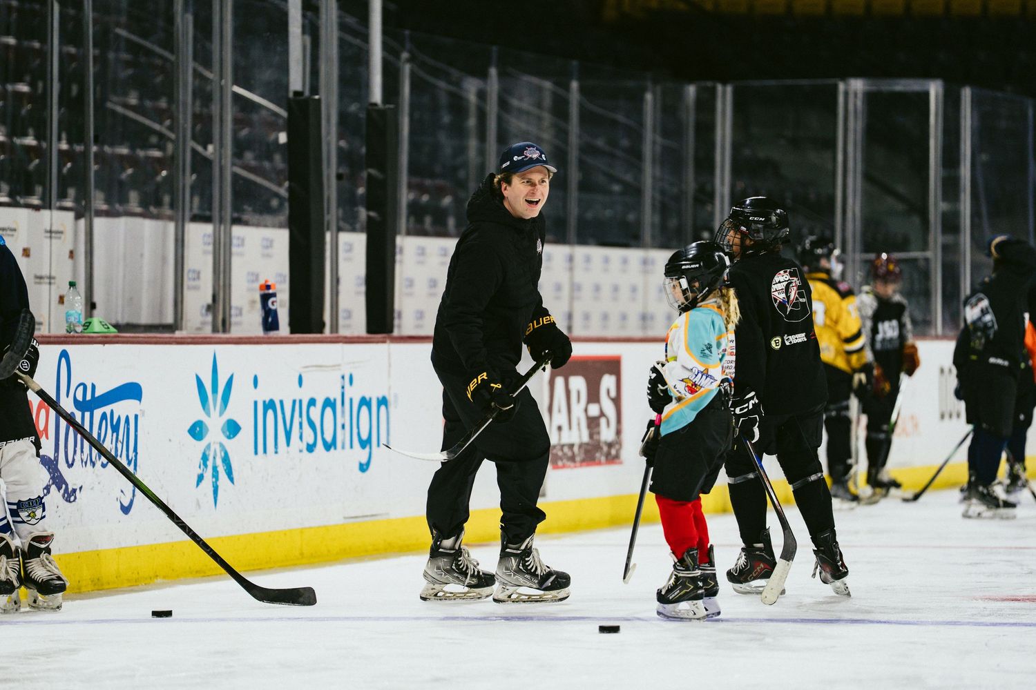 Hockey coach instructing group of young players during youth ice hockey practice session.