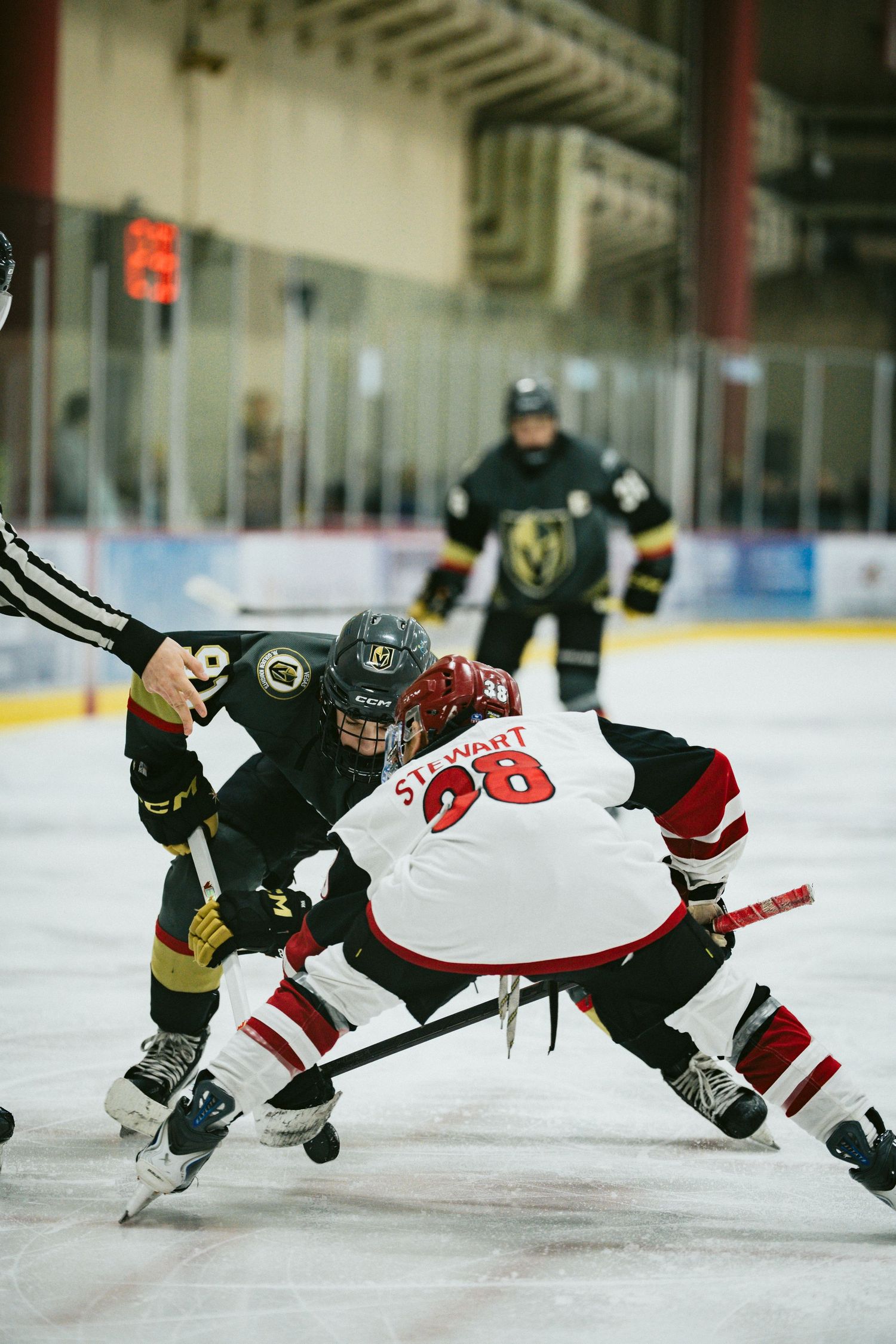 Two hockey players battle for position during an intense face-off on the ice.