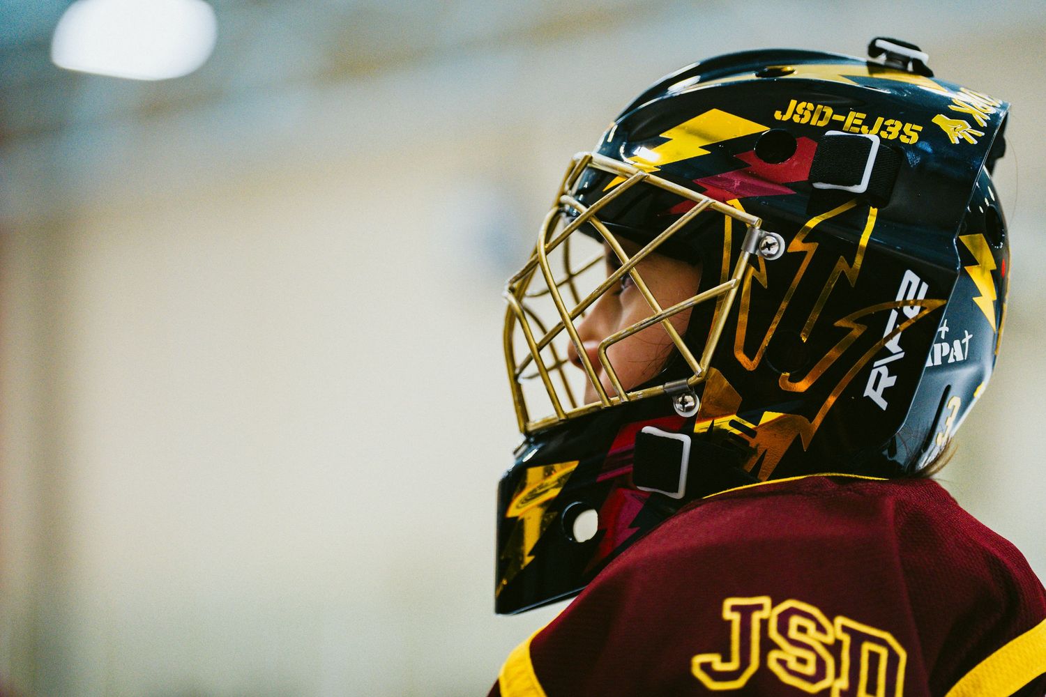 Close-up view of hockey helmets with yellow and black designs during a game.