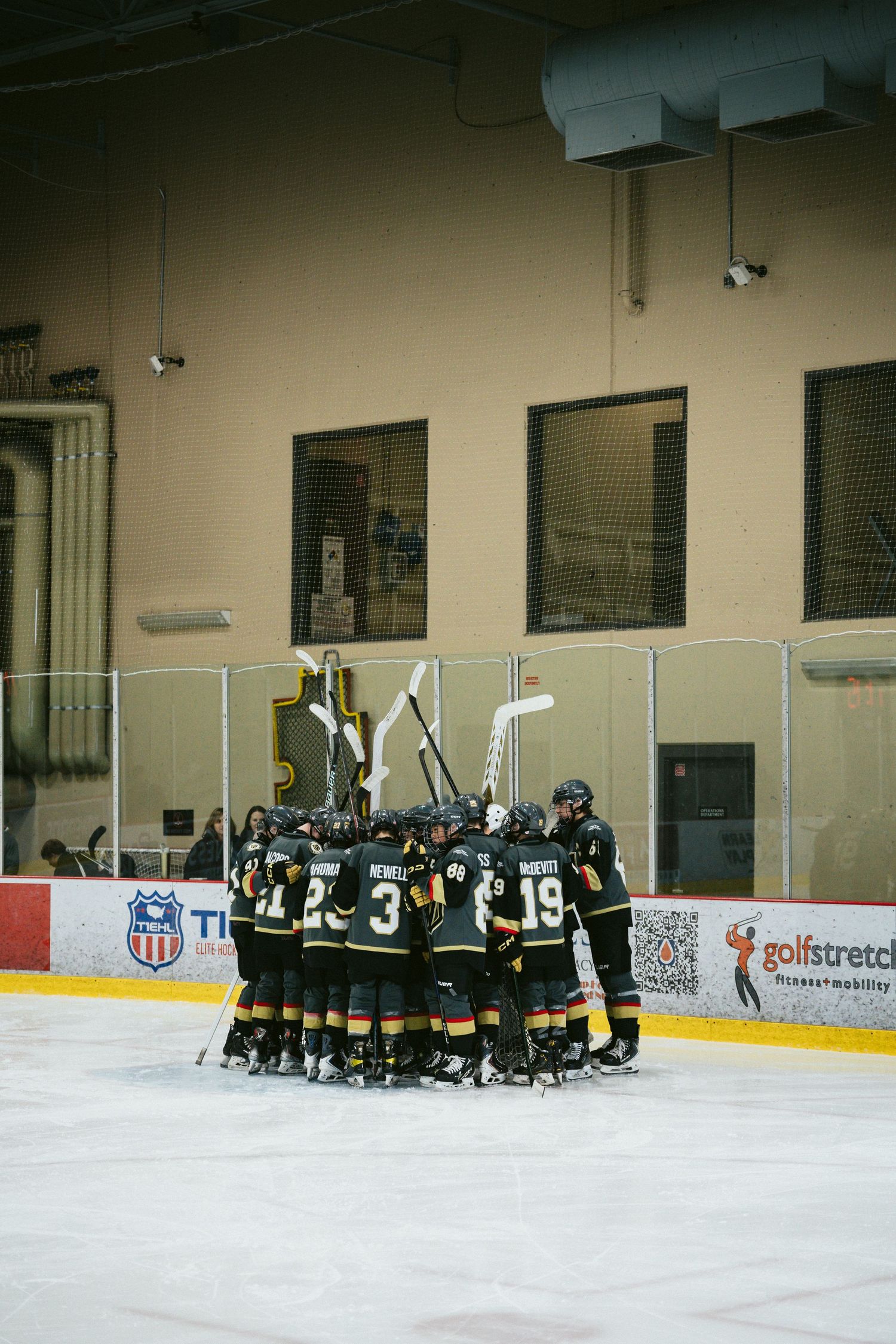 Hockey team huddles together on ice rink during practice or game break.