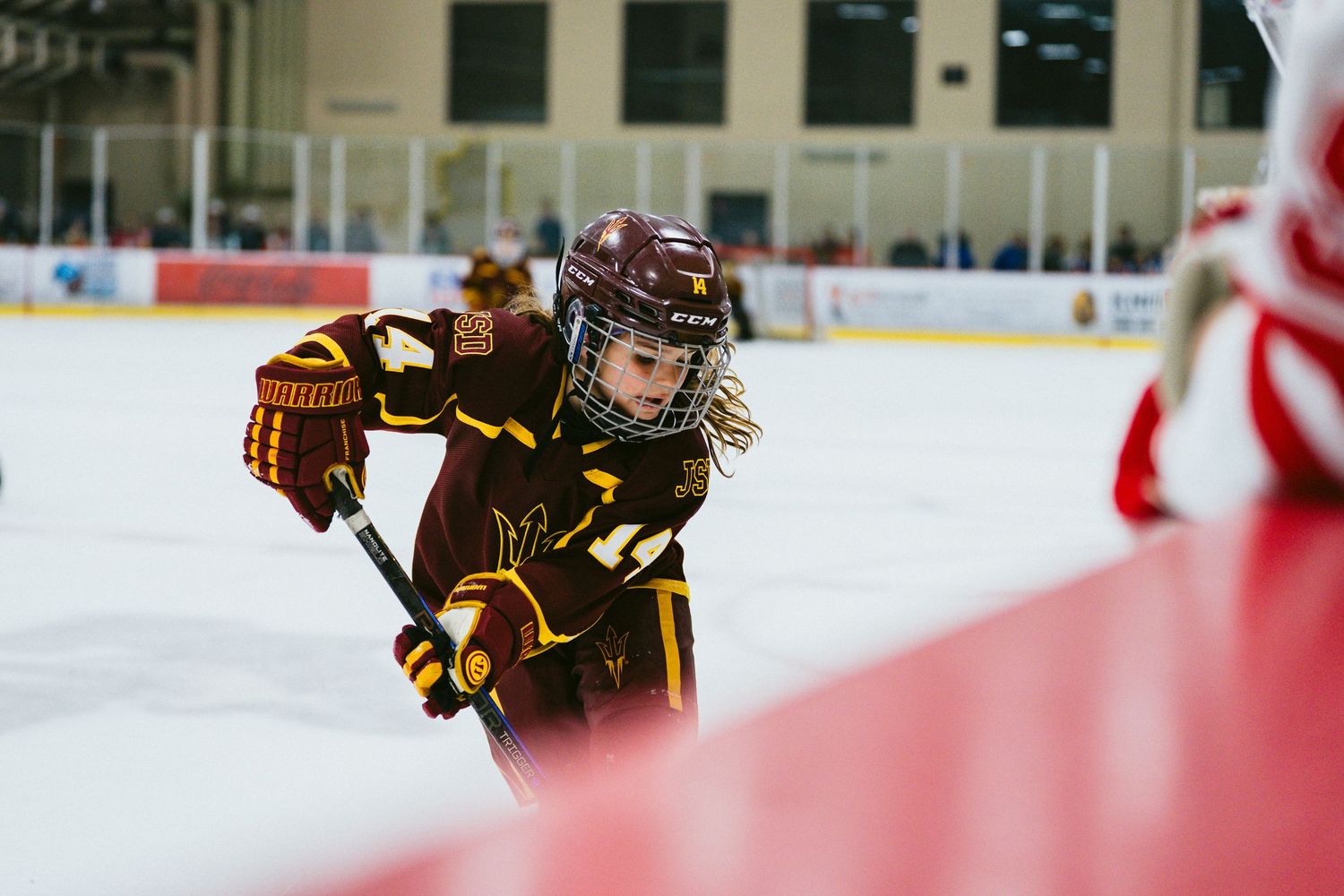 Close-up action shot of hockey players in black and red uniforms during intense gameplay.