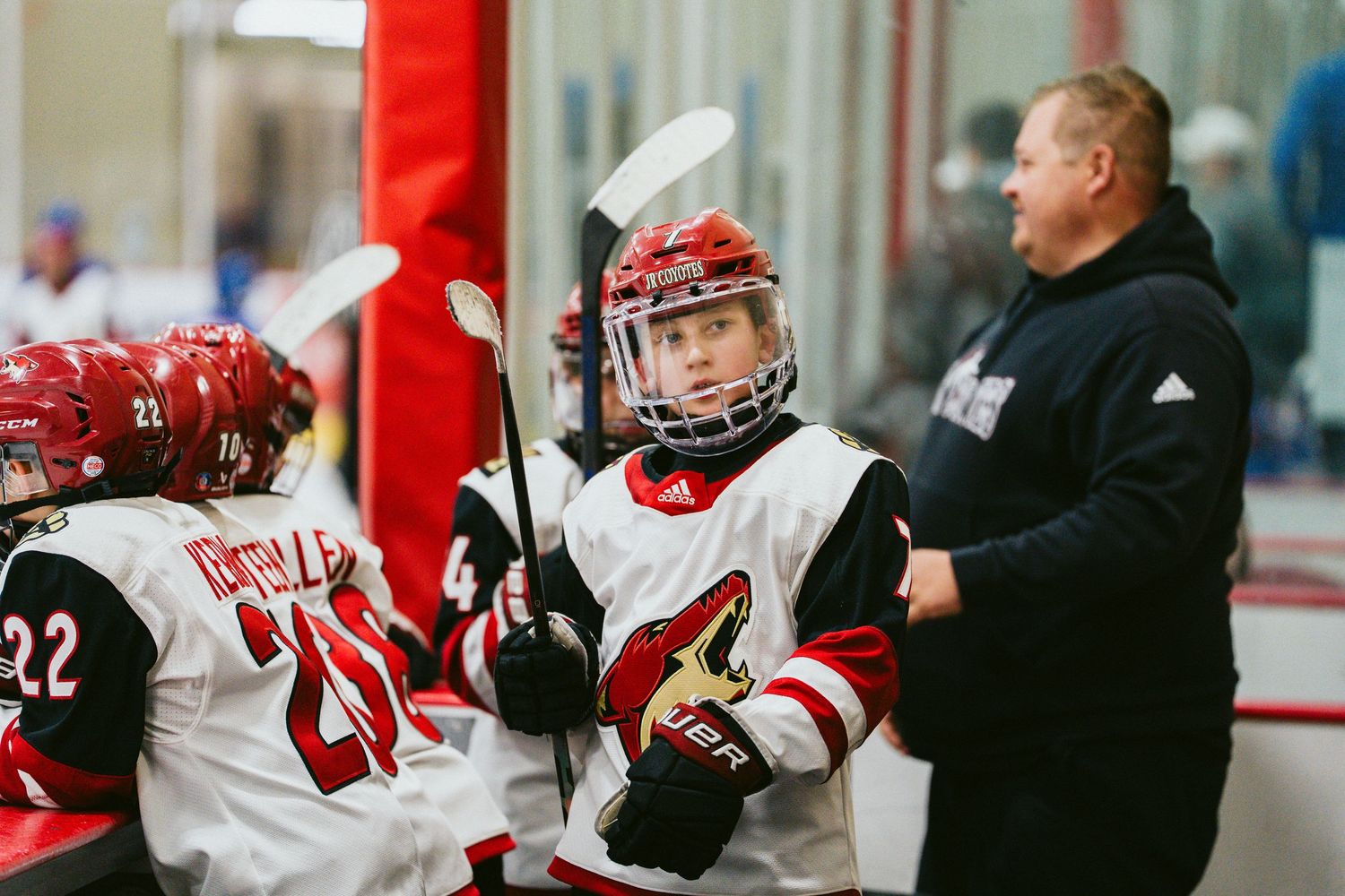 Hockey players and coaches gather on the ice during a practice session or game break.