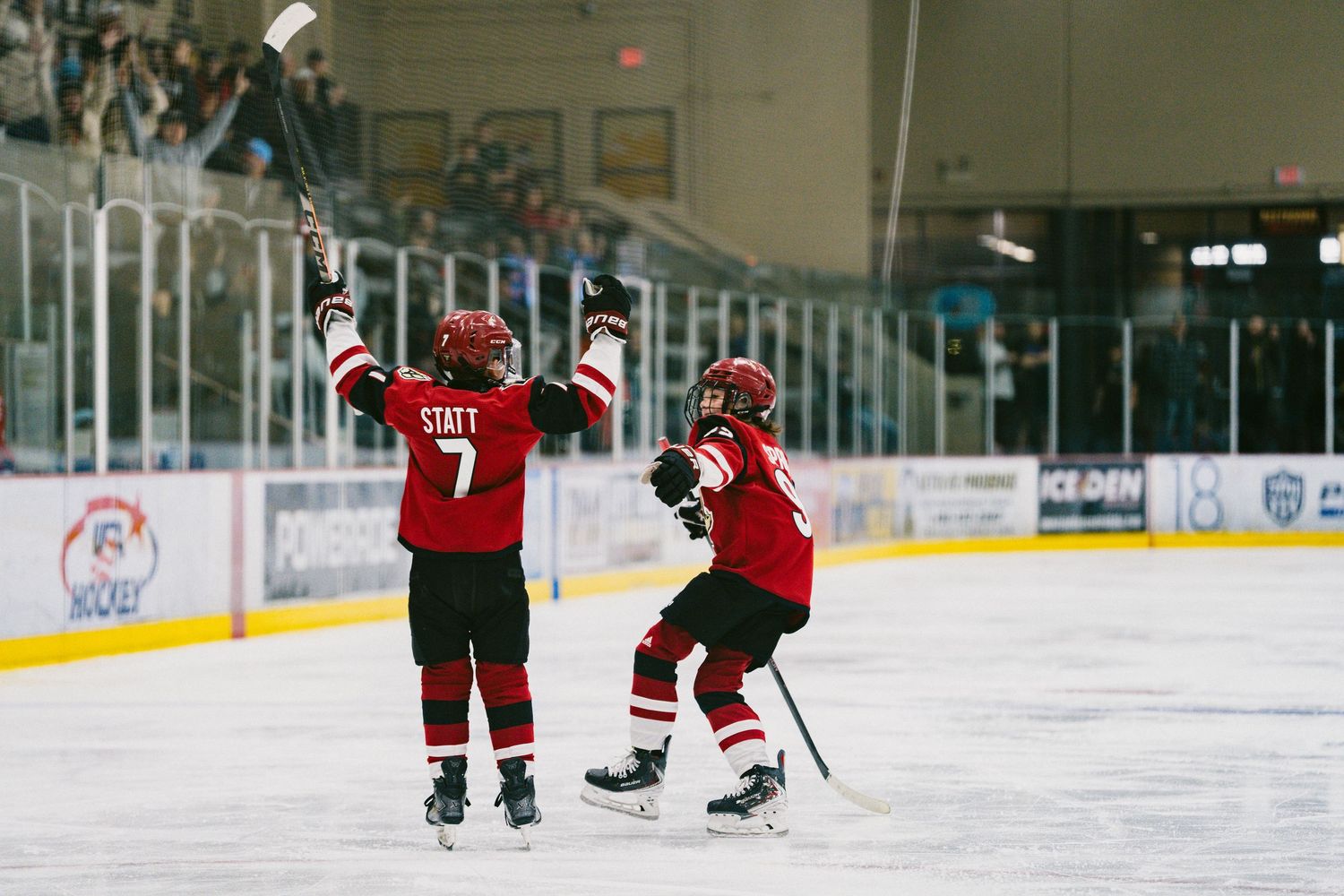 Young hockey players practice skating drills on an indoor ice rink during training session.