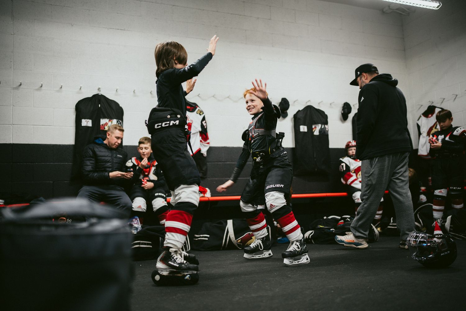 Hockey players celebrating in locker room wearing red and white uniforms.