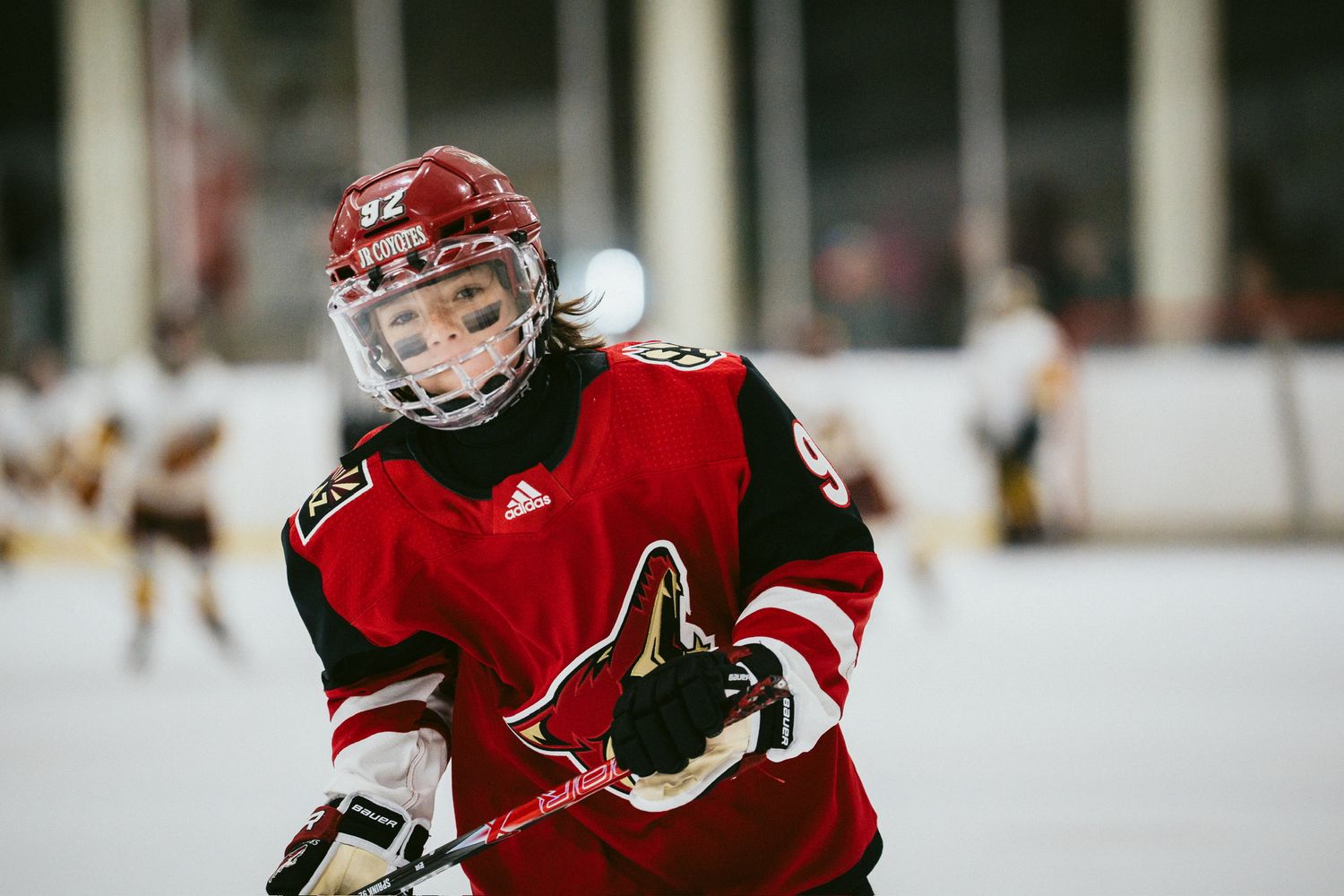 Hockey player in red Coyotes jersey skating during intense game action.