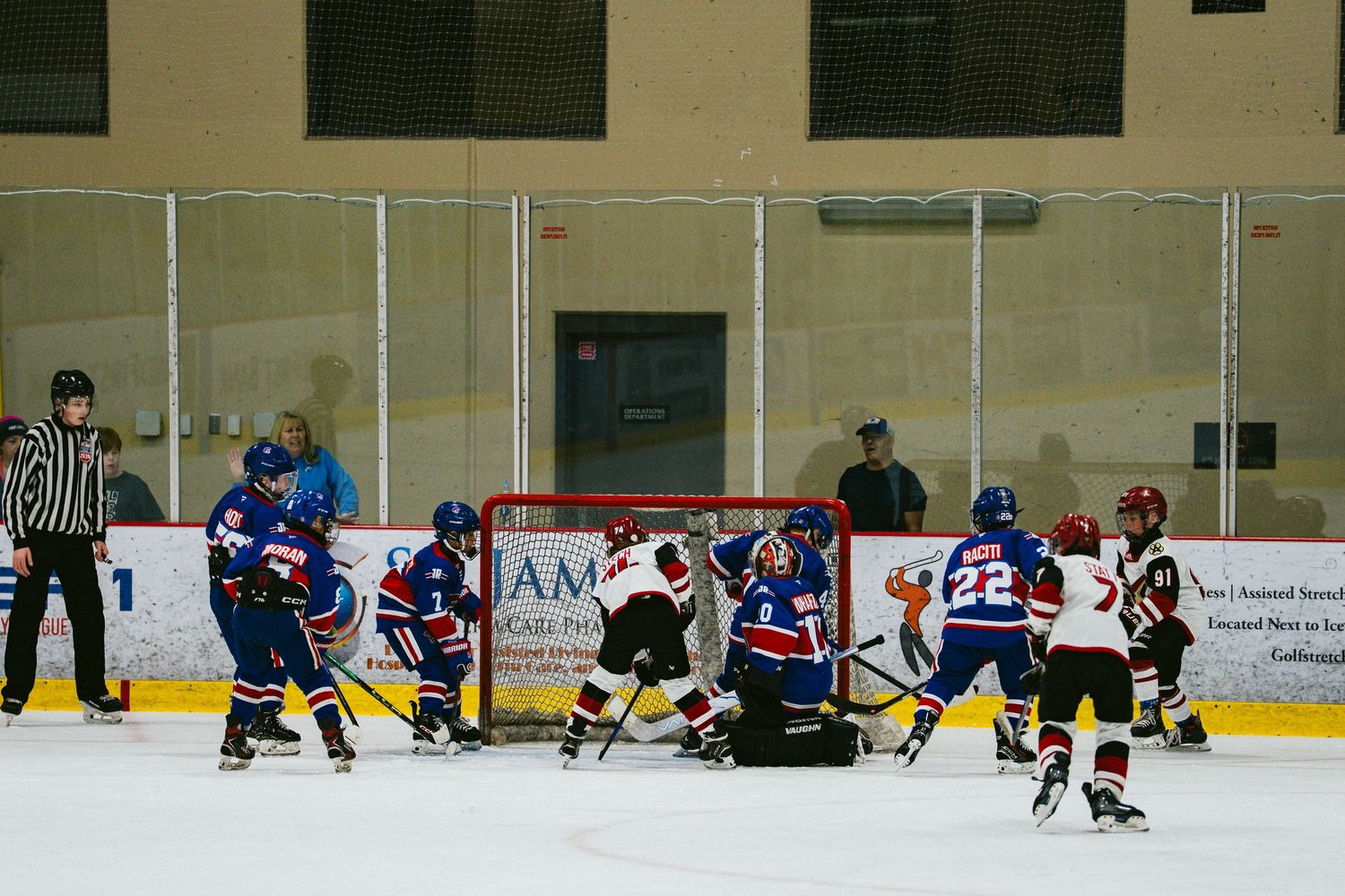 Hockey players crowd around the goal during an intense scoring attempt.